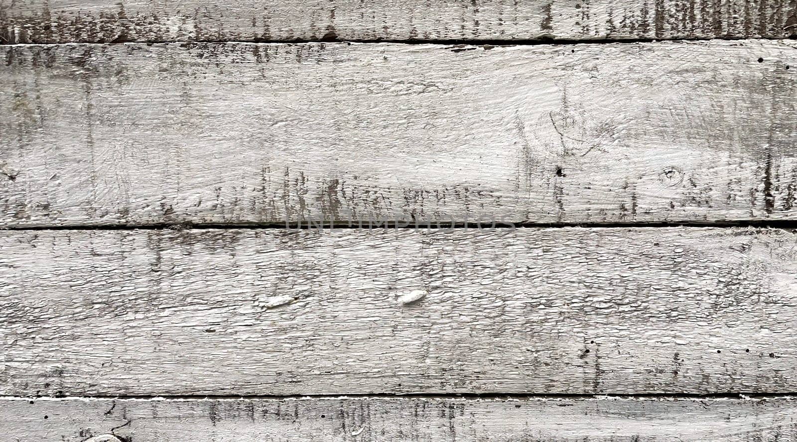 A close-up view of weathered white wooden planks. The texture of the wood is prominently displayed, showcasing the natural grain, knots, and imperfections that give it a rustic and aged appearance. The white paint is worn and chipped in places, adding to the vintage and distressed look. This background is ideal for use in design projects that require a natural, rustic, or shabby chic aesthetic.