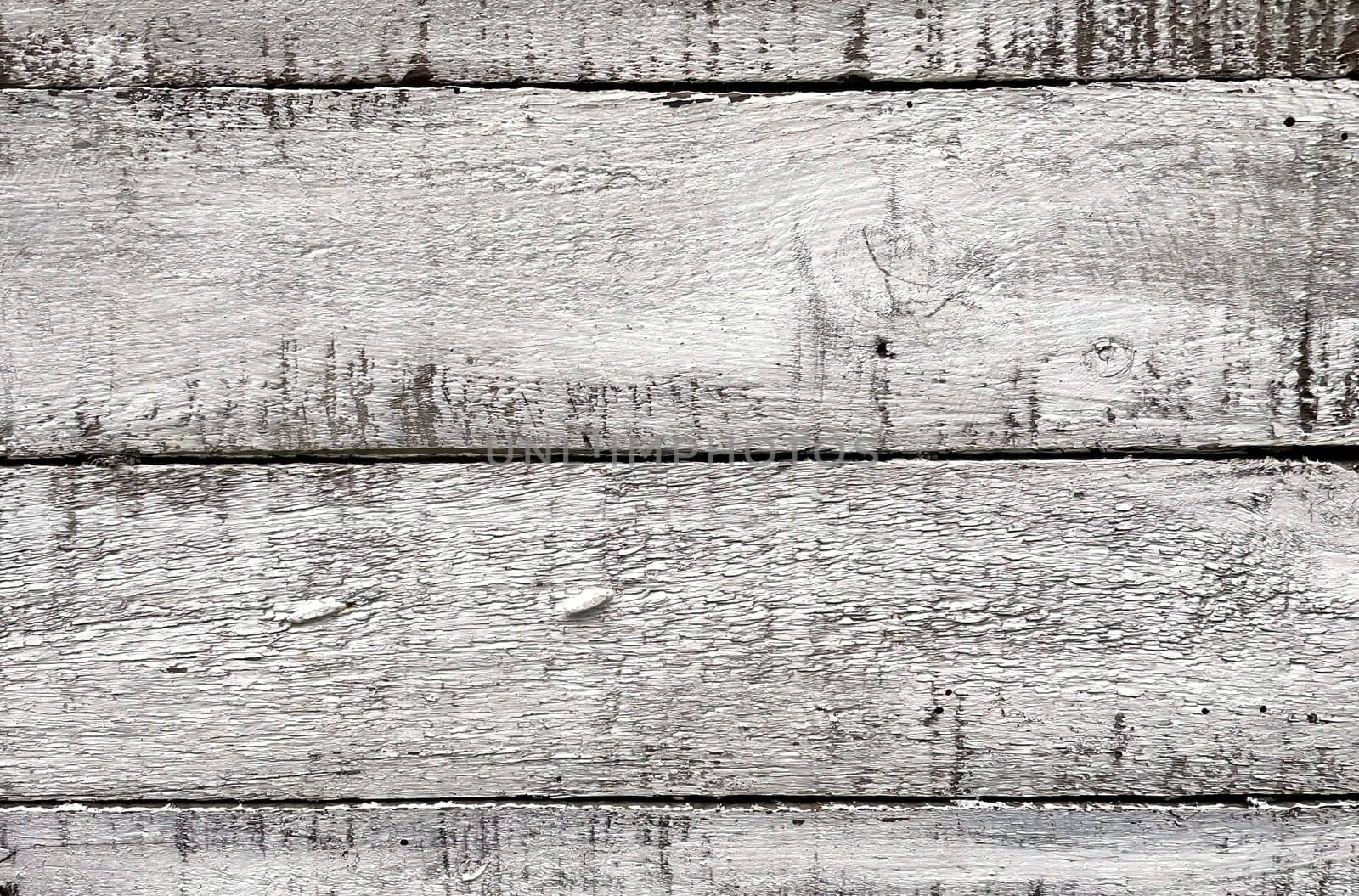 A close-up view of weathered white wooden planks. The texture of the wood is prominently displayed, showcasing the natural grain, knots, and imperfections that give it a rustic and aged appearance. The white paint is worn and chipped in places, adding to the vintage and distressed look. This background is ideal for use in design projects that require a natural, rustic, or shabby chic aesthetic.
