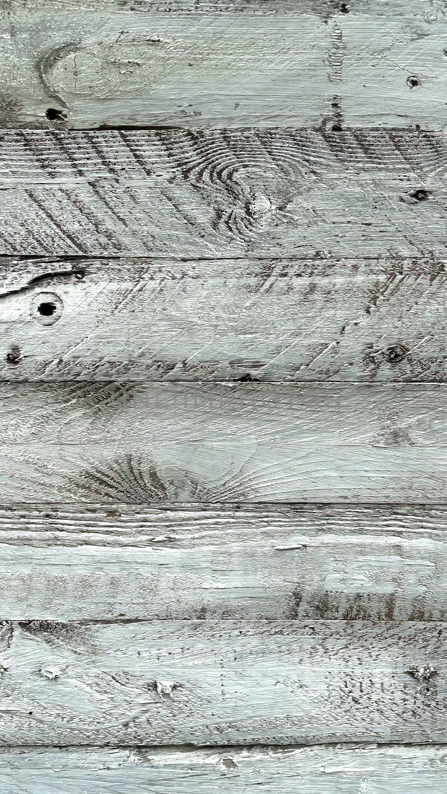 A close-up view of weathered white wooden planks. The texture of the wood is prominently displayed, showcasing the natural grain, knots, and imperfections that give it a rustic and aged appearance. The white paint is worn and chipped in places, adding to the vintage and distressed look. This background is ideal for use in design projects that require a natural, rustic, or shabby chic aesthetic.