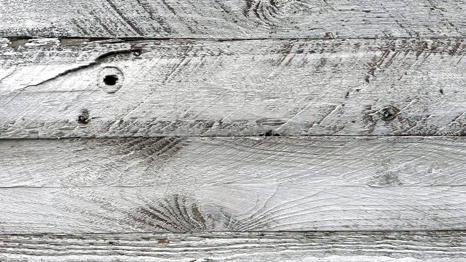 A close-up view of weathered white wooden planks. The texture of the wood is prominently displayed, showcasing the natural grain, knots, and imperfections that give it a rustic and aged appearance. The white paint is worn and chipped in places, adding to the vintage and distressed look. This background is ideal for use in design projects that require a natural, rustic, or shabby chic aesthetic.