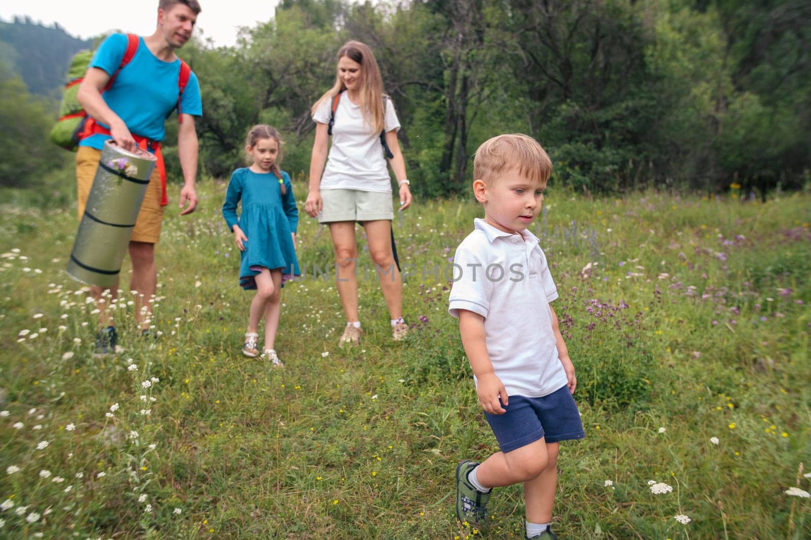 A wonderfully joyous family is joyfully exploring a vibrant, colorful meadow during an exciting nature hike