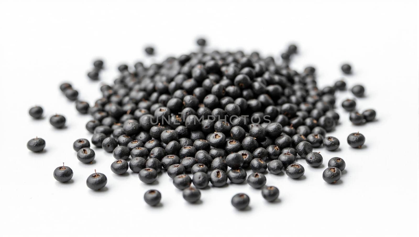 A large pile of black berries is spread across a white surface, highlighting their deep color and unique texture. The arrangement emphasizes the natural shape and sheen of each berry.