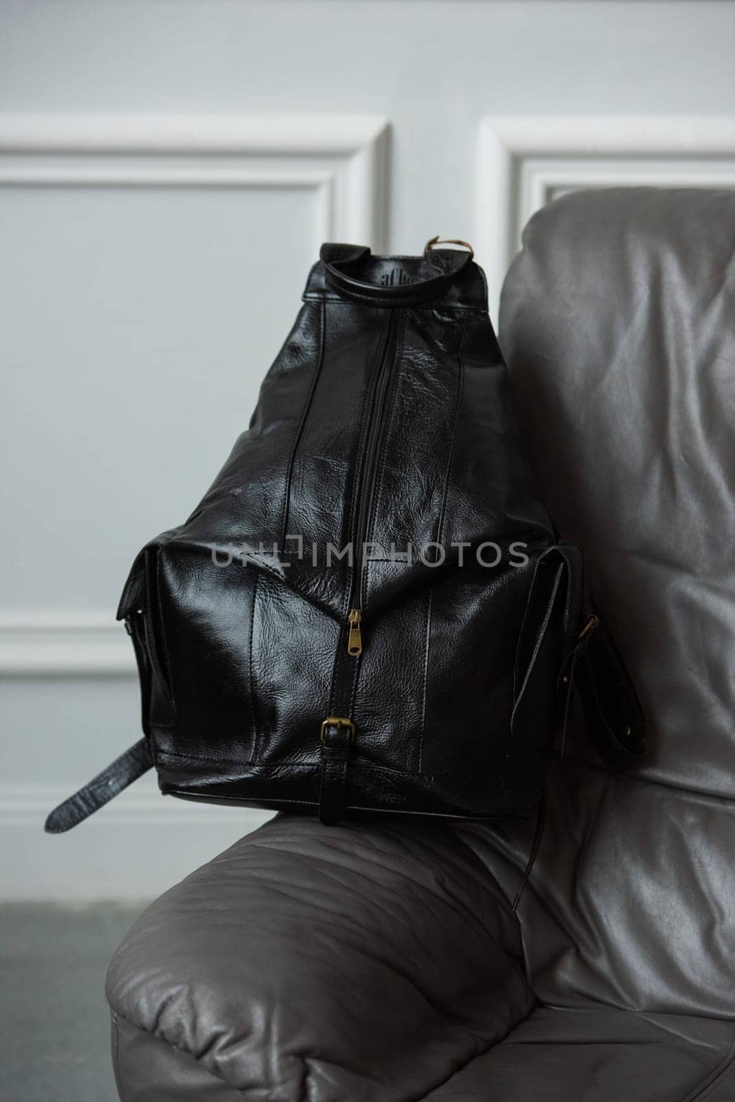 Black leather backpack on chair, close up..