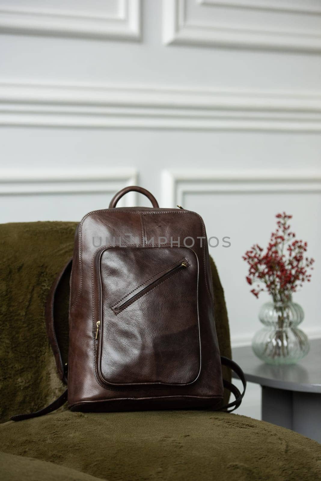 Brown leather backpack on chair, close up.