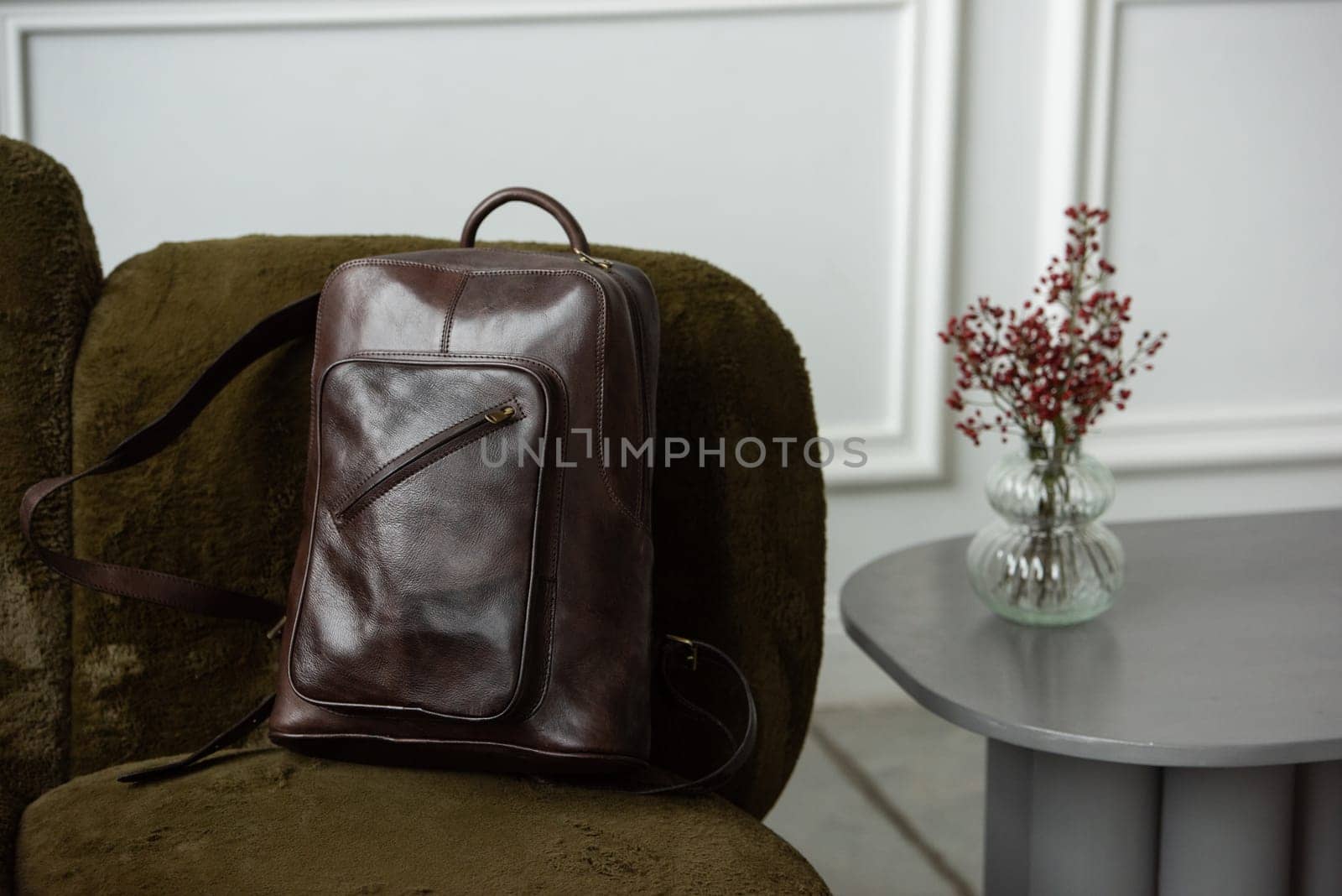 Brown leather backpack on chair, close up.