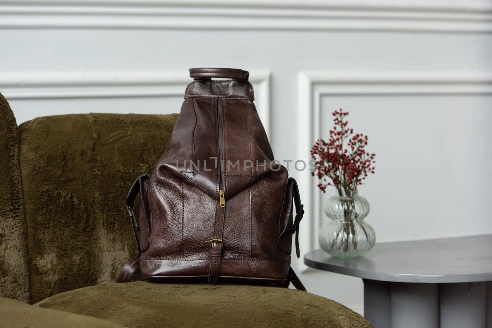 Brown leather backpack on sofa, close up.
