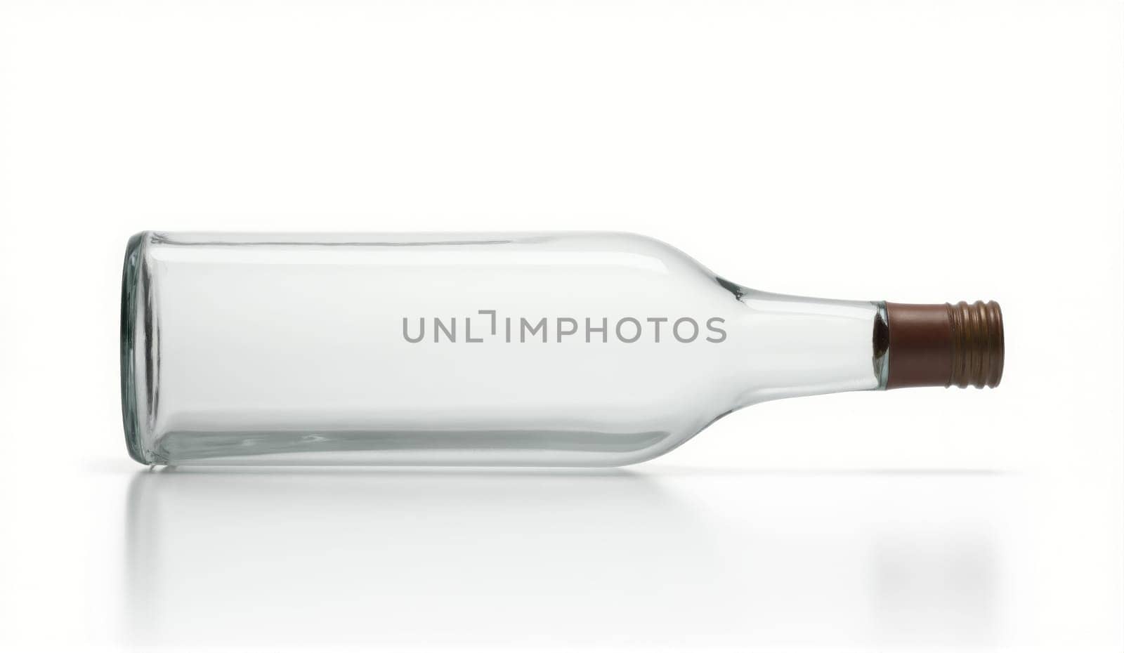 A clear glass bottle lies on its side on a reflective surface, emphasizing its shape and design. The bottle has a simple structure, showcasing transparency and elegance.
