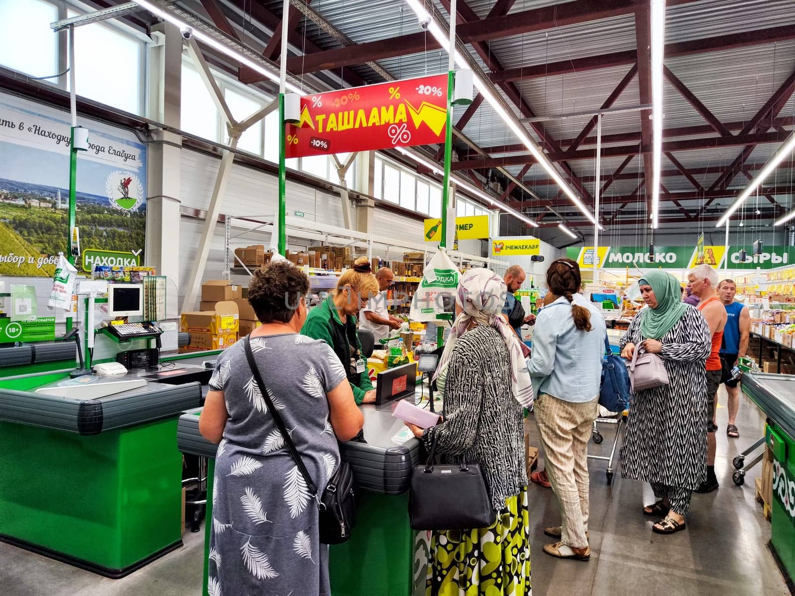 Yelabuga, Russia - July 21, 2024: Customers engage with the cashier at a busy grocery store in Yelabuga, Russia, creating a vibrant shopping atmosphere.