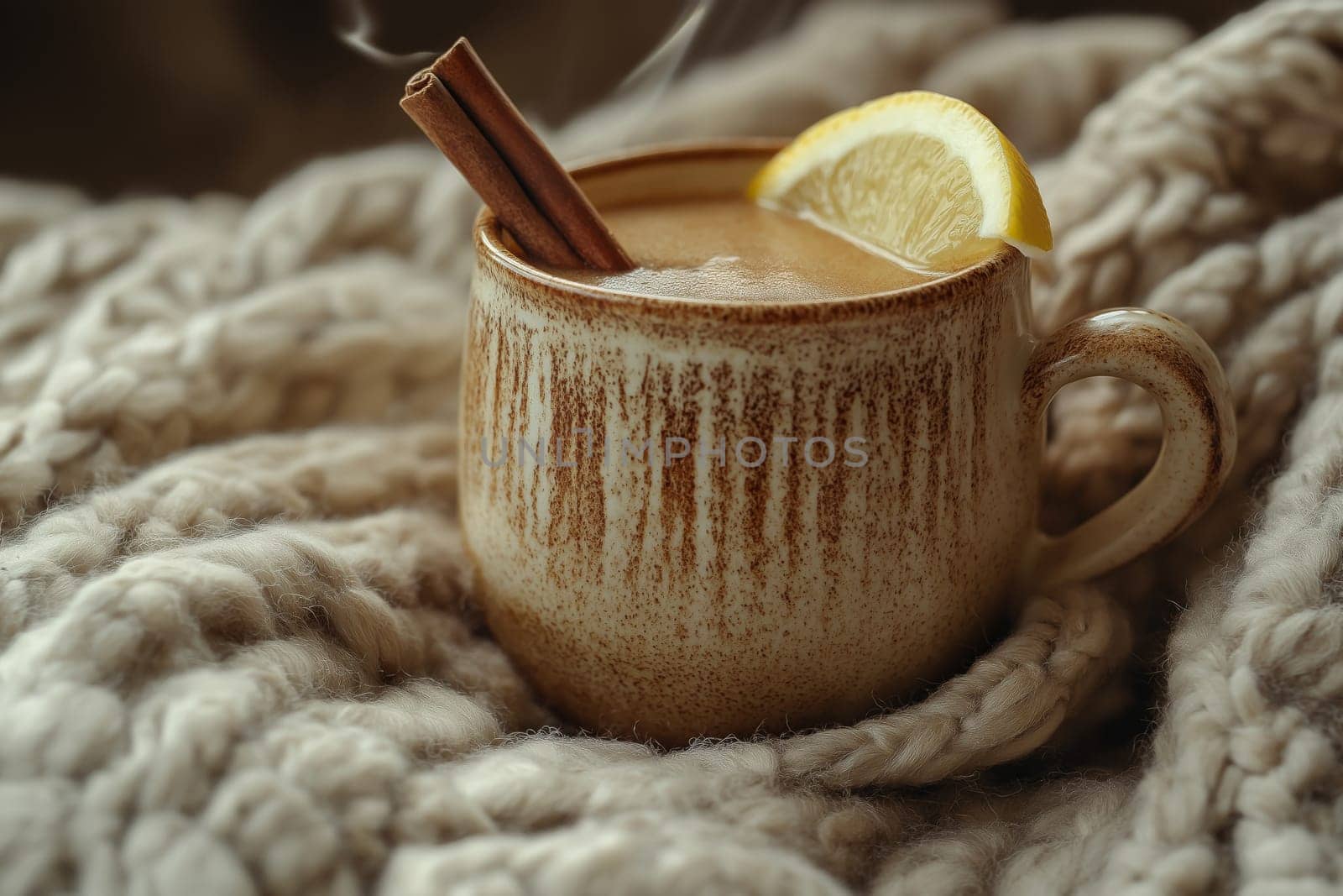 A warm mug of herbal tea rests on a soft, textured blanket. The steaming drink is adorned with a cinnamon stick and a slice of lemon, inviting relaxation and comfort.