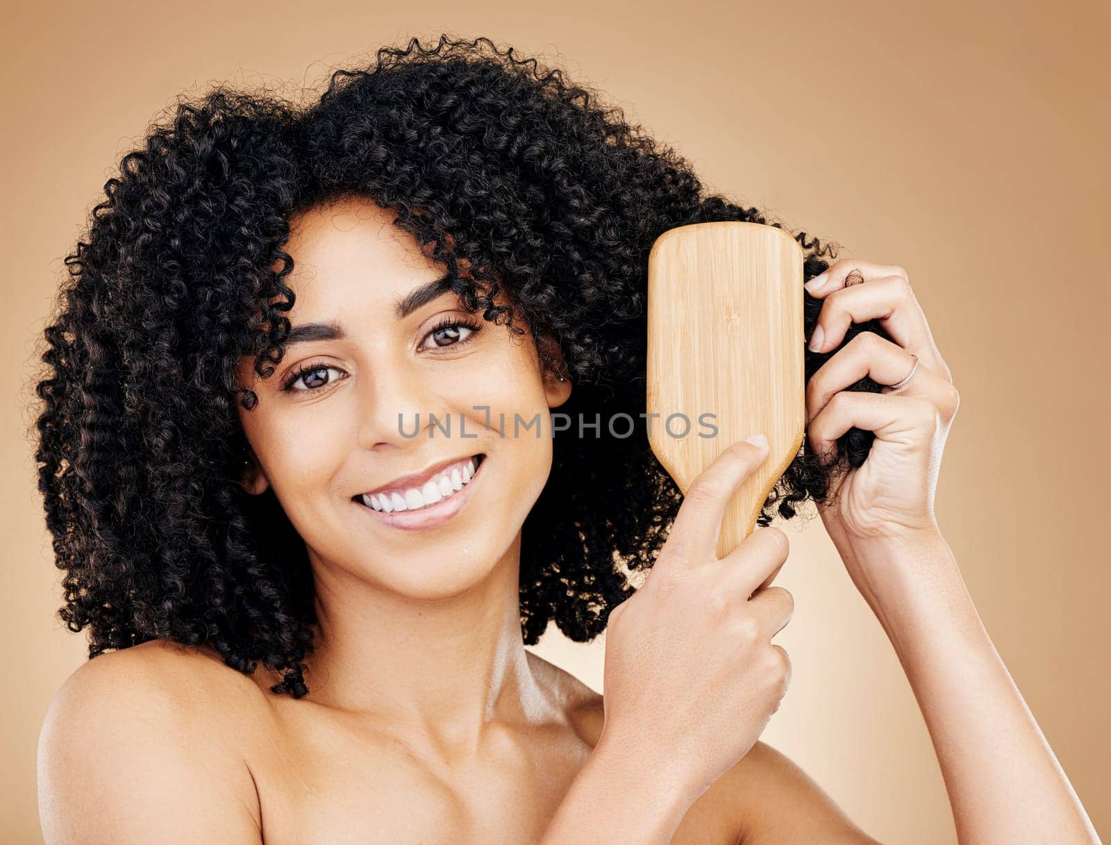 Woman, portrait and brush hair, curly with shine and beauty, smile for salon treatment and strong texture on studio background. Face, skin and growth, haircare and cosmetology with cosmetic tools by YuriArcurs