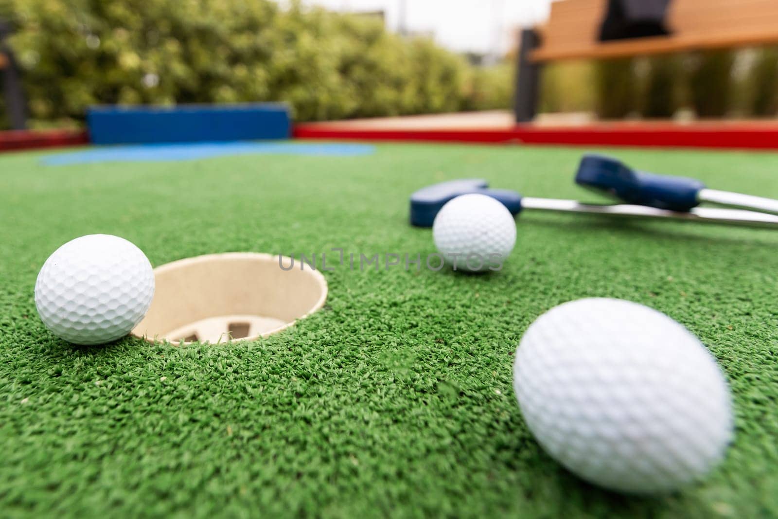 Fun vacation entertainment for summertime. Playing mini golf on green grass outdoors. Setting goals and winning lifestyle concept. Competition at golf course: two crossed sticks. Blank space for copy. by Andelov13