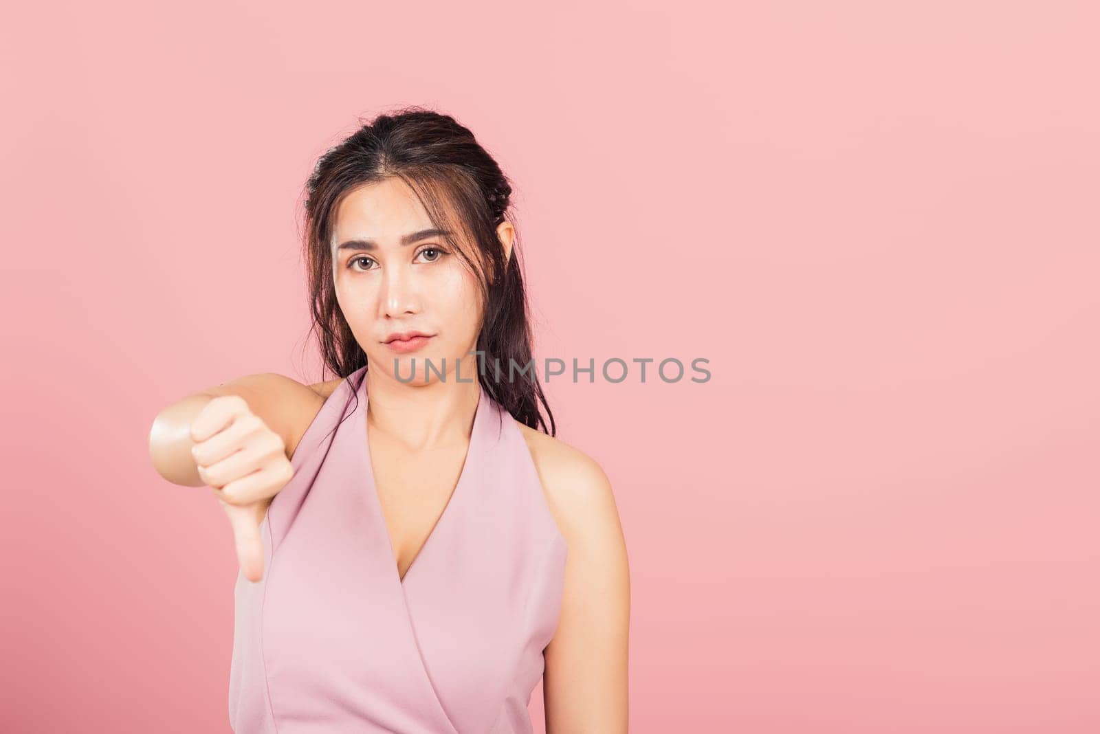 woman unhappy, negative gesture showing finger thumbs down by Sorapop