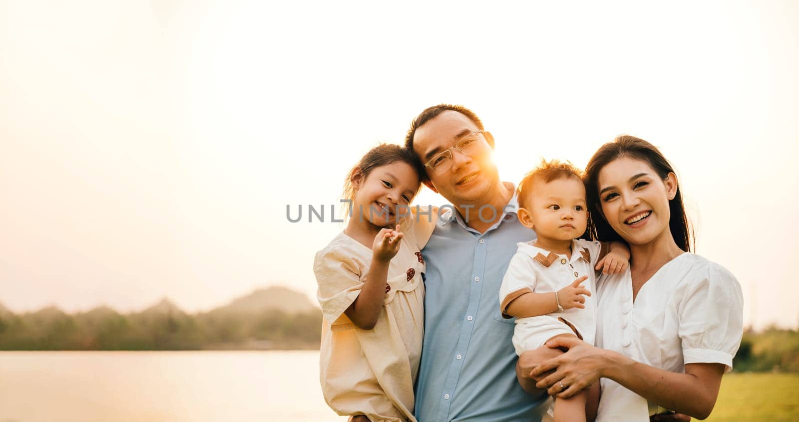 A happy group of children and parents laughing and having fun together in a park, joyful family of four enjoying the warmth of the sunshine and the beauty of the outdoors, Family Day