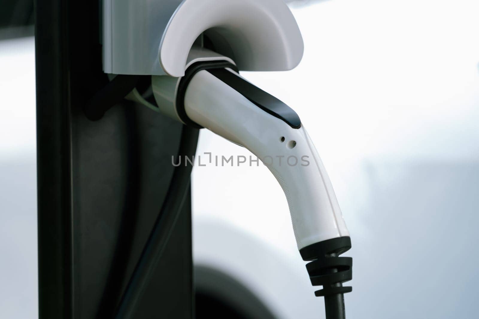 Closeup EV charging station with charger plug connected power sauce. Synchronos by biancoblue
