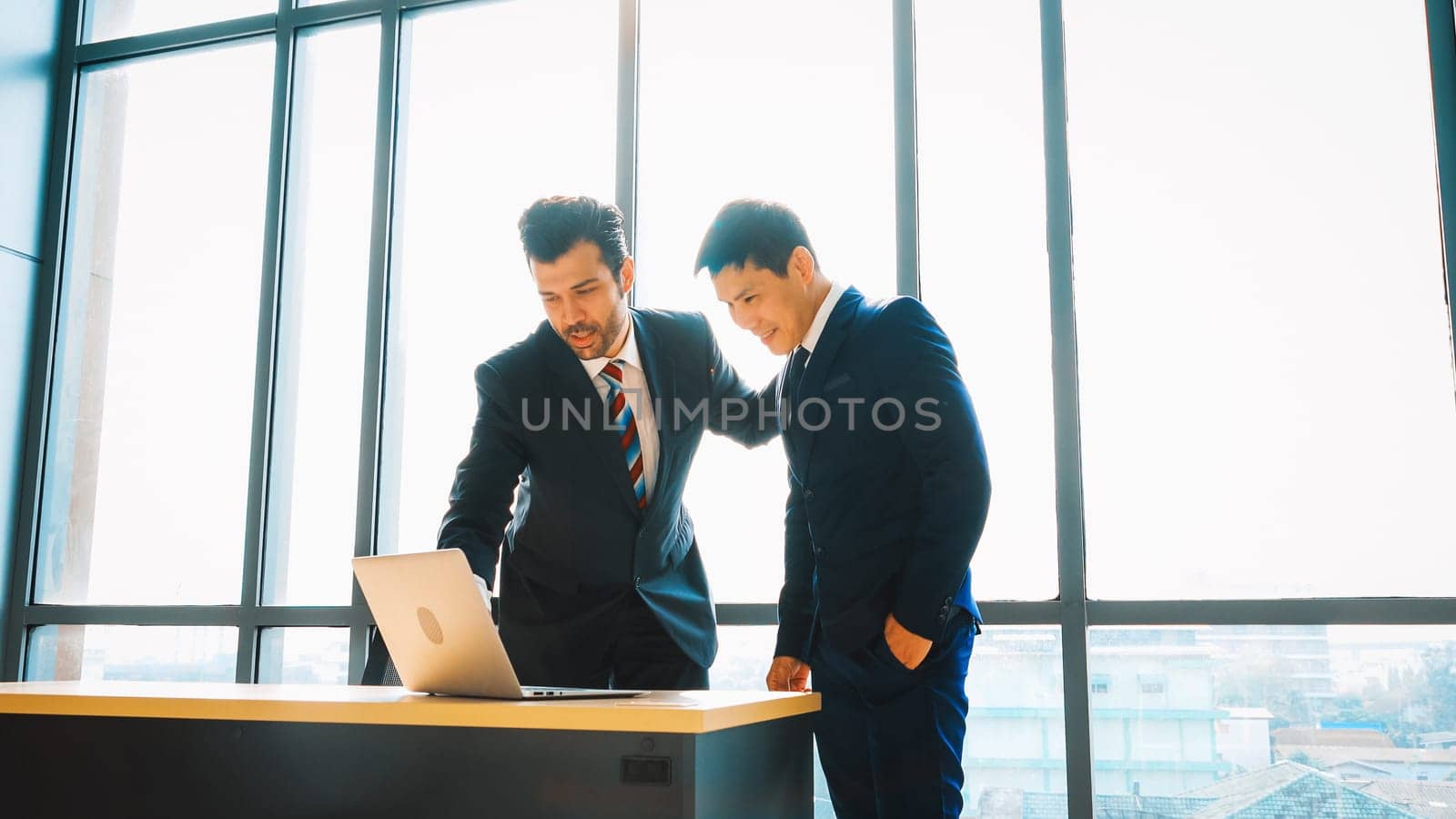 Two business people talk project strategy at office meeting room. Businessman discuss project planning with colleague at modern workplace while having conversation and advice on financial report. Jivy