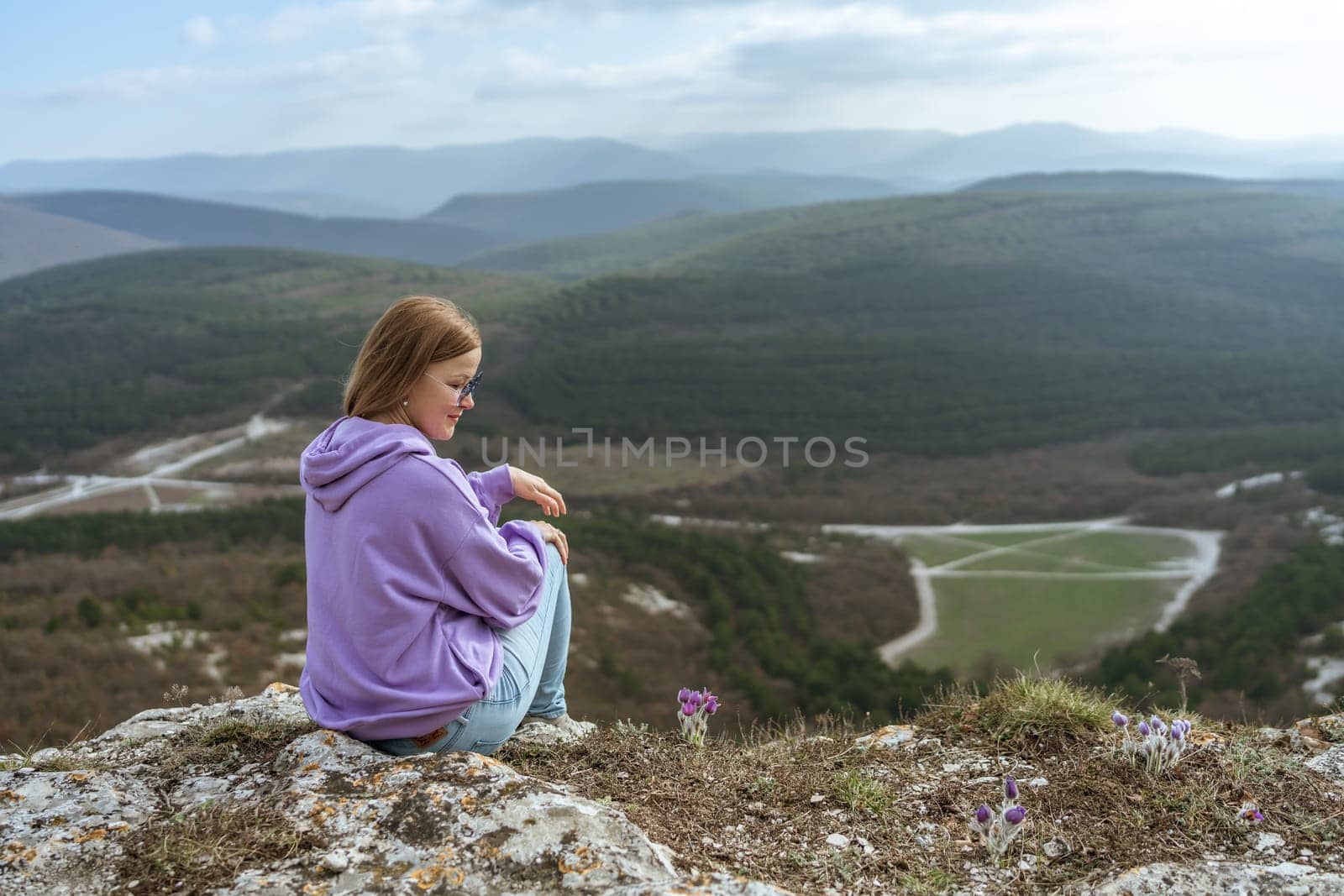 Girl on mountain peak looking at beautiful mountain valley in fog at sunset in summer. Landscape with sporty young woman, foggy hills, forest, sky. Travel and tourism, hiking.