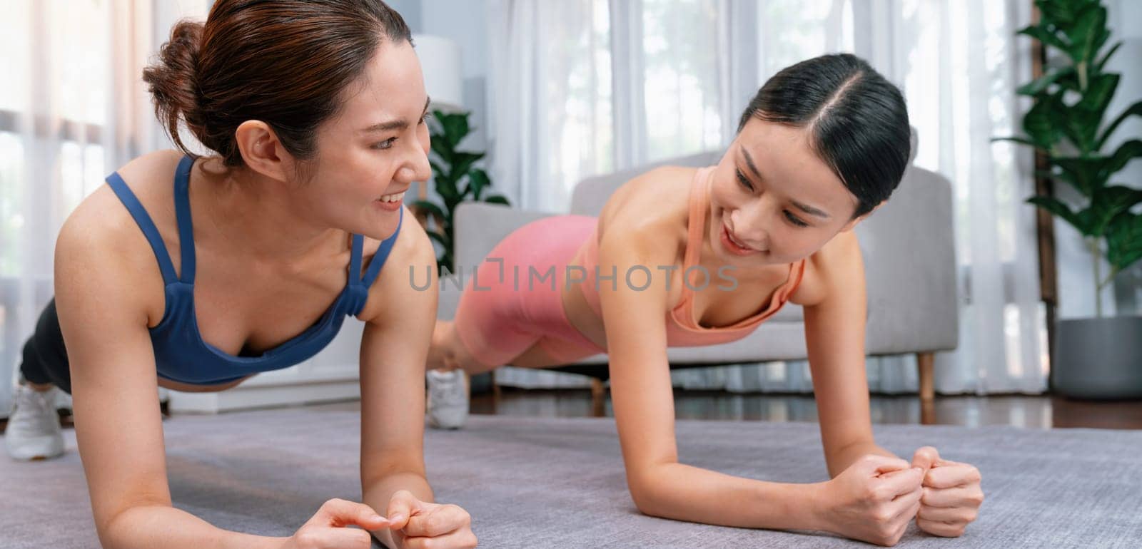 Fit young asian woman planing on the living room floor with her trainer or exercise buddy. Healthy lifestyle workout training routine at home. Balance and endurance exercising concept. Vigorous