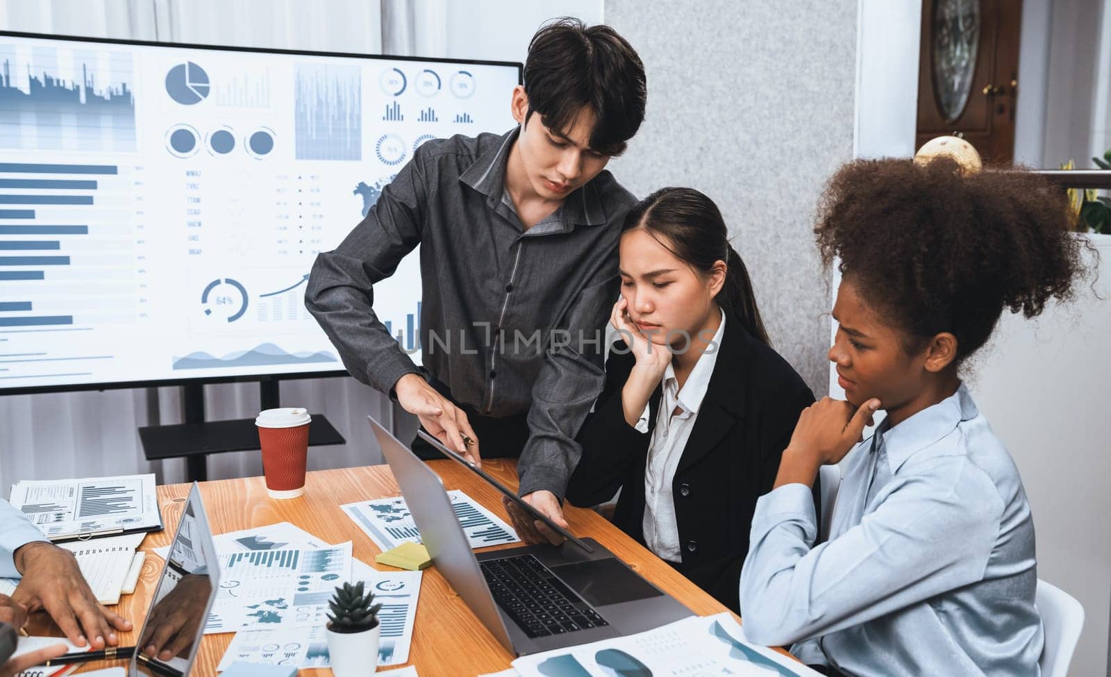 Diverse businesspeople analyzing financial dashboard data on laptop in serious meeting, confused and worried. Difficult challenge in corporate world. Hectic analysis or problem in workplace. Concord