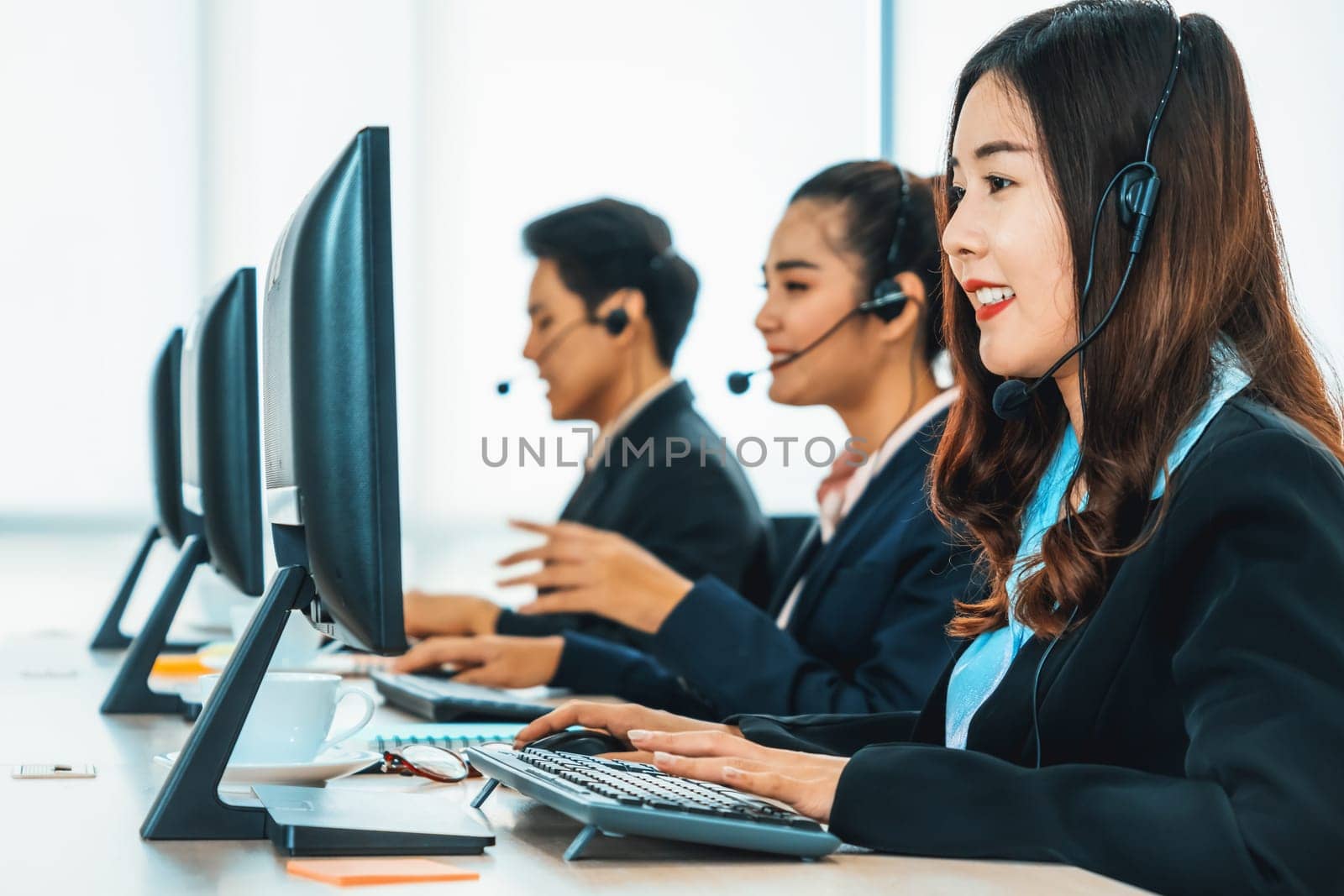 Business people wearing headset working in office to support remote customer or colleague. Call center, telemarketing, customer support agent provide service on telephone video conference call. Jivy