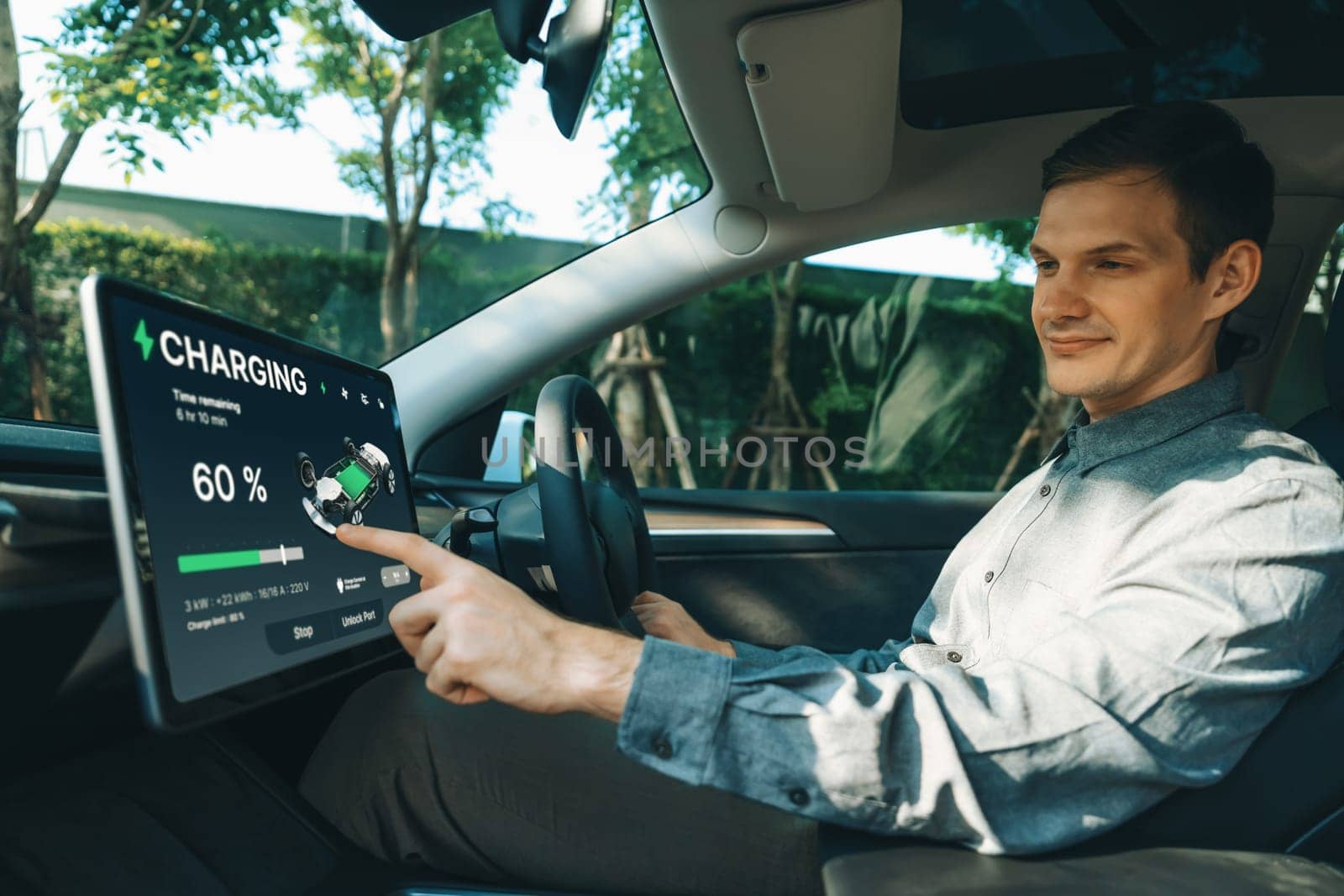 Electric car driver checks battery charging status, range and charging limit on app screen in the car. Smart technology device show EV car recharging data of electric storage in car battery innards.