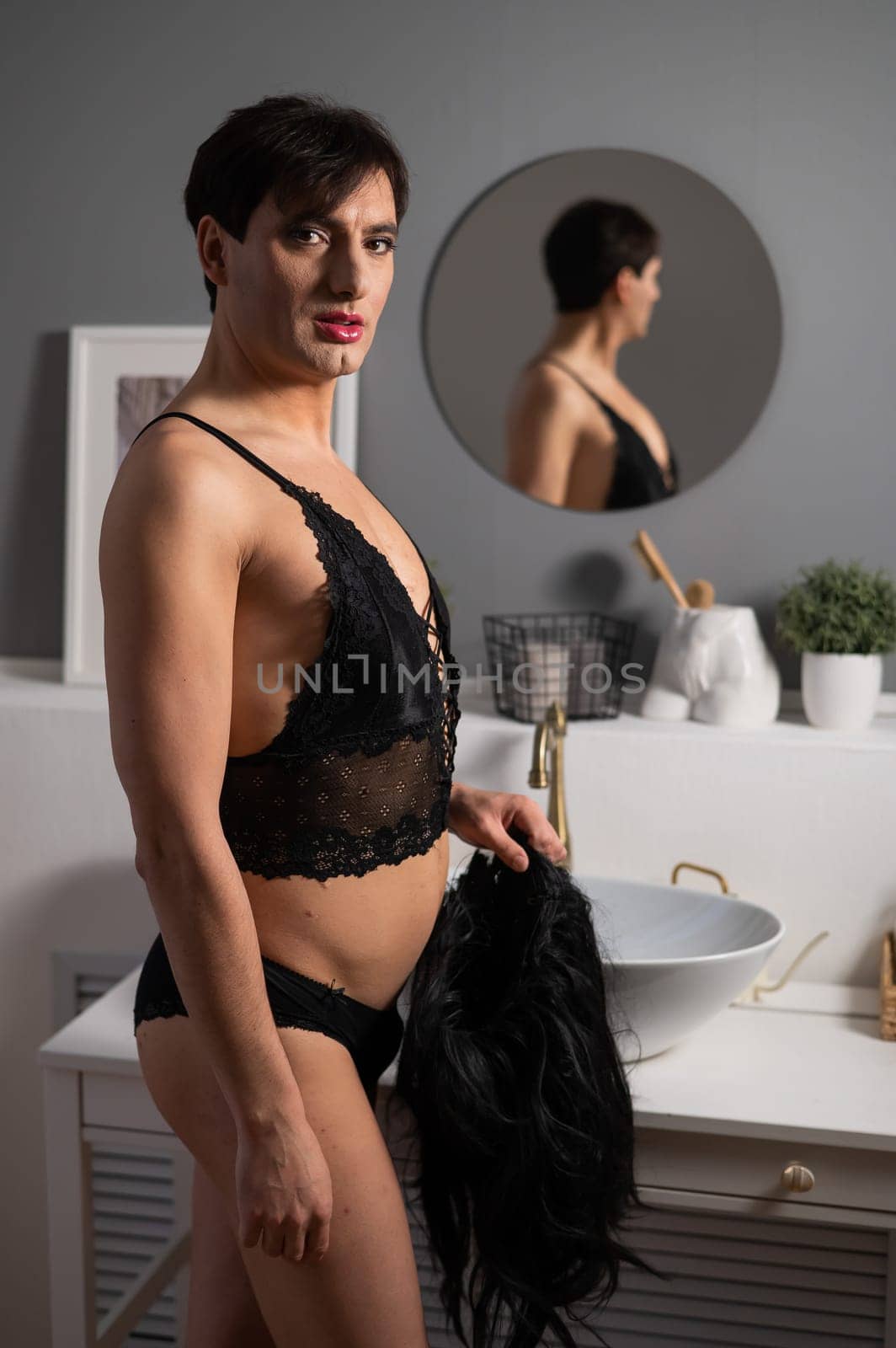 Homosexual preening in front of the mirror. A transgender man combing a wig