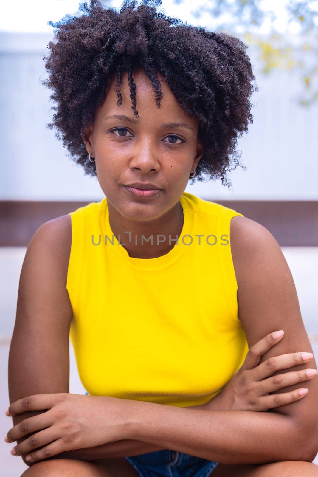 Portrait of black woman with a smiling, thoughtful expression. Focus on her facial features and natural beauty, captured outdoors with soft lighting and an urban background.