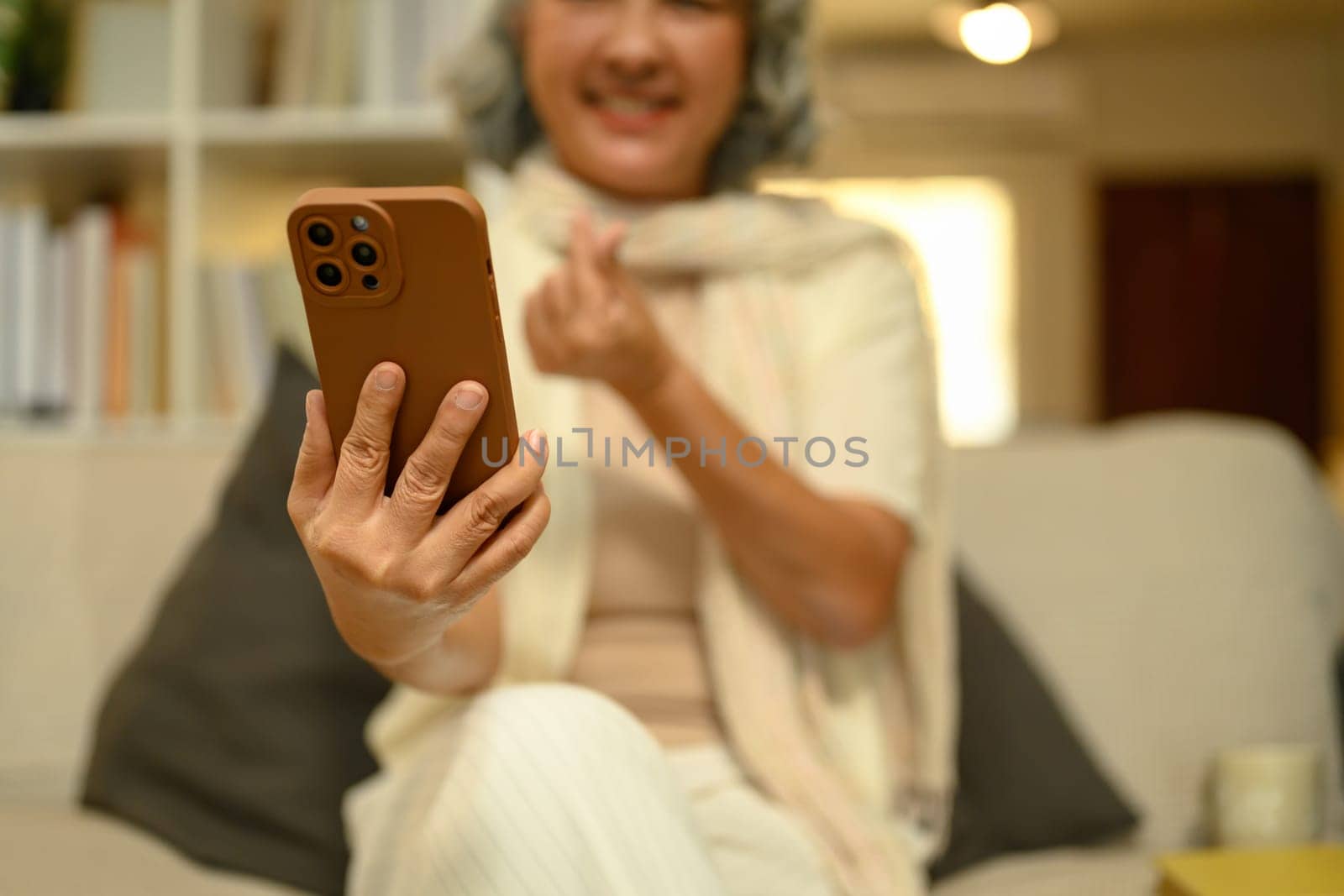 Smiling senior woman having video call on her mobile phone at home.