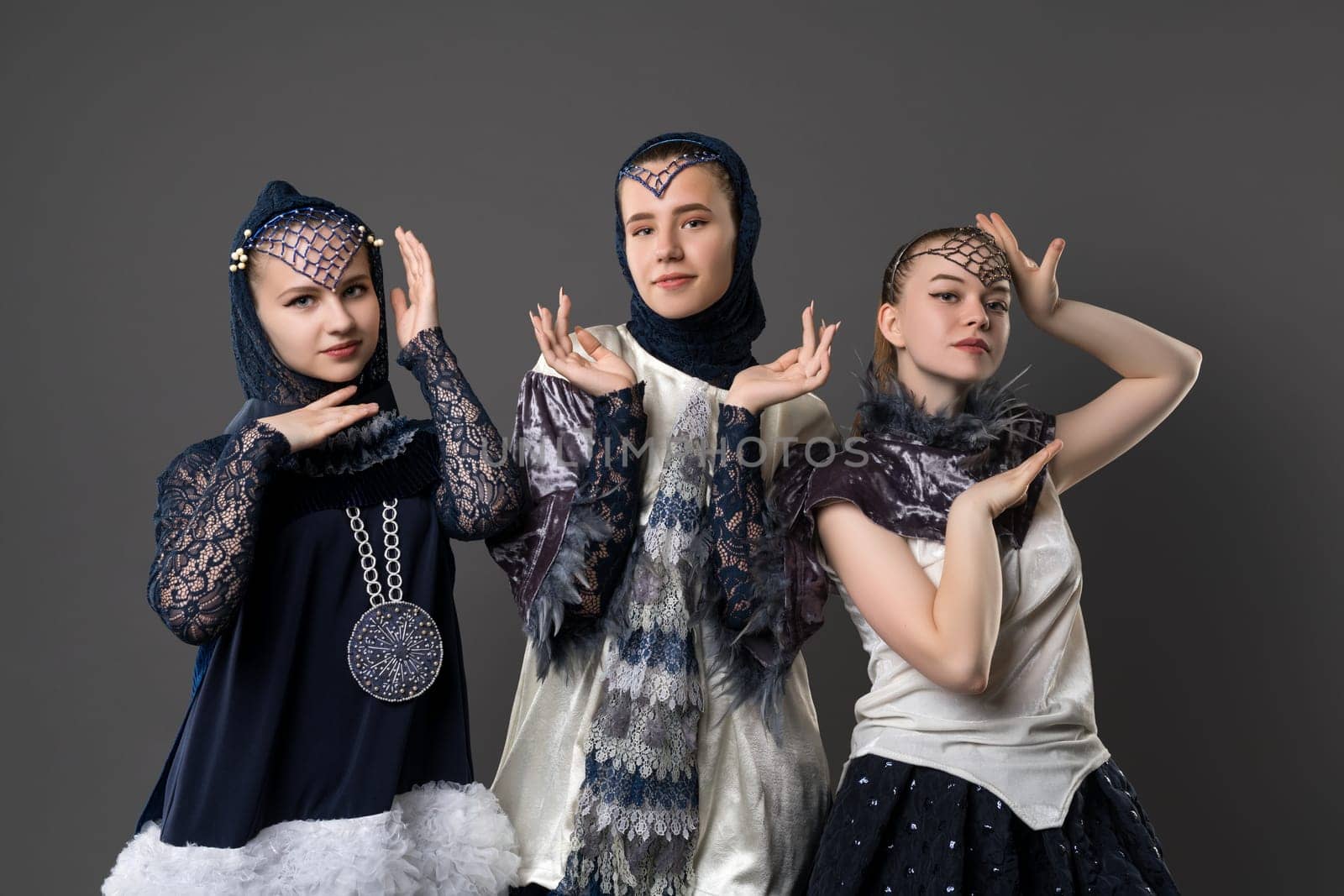 Shot of pretty teenagers in artistic design dresses against gray background