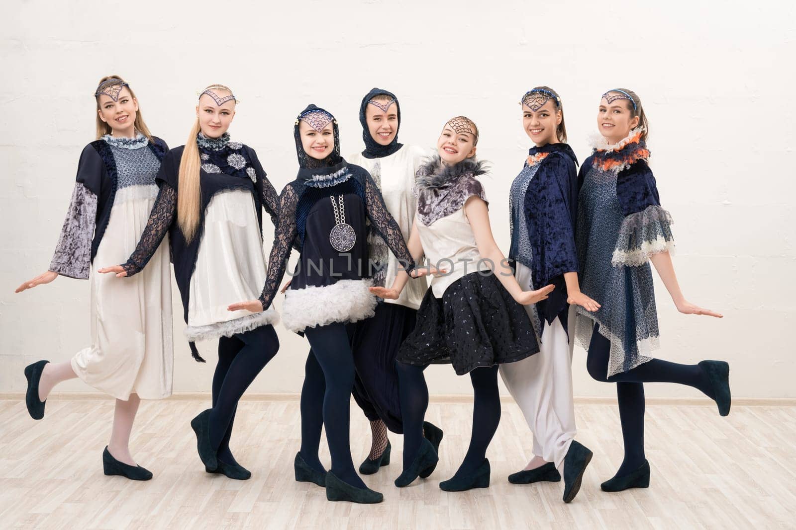 Group of beautiful girls in artistic design costumes isolated full-length view on white