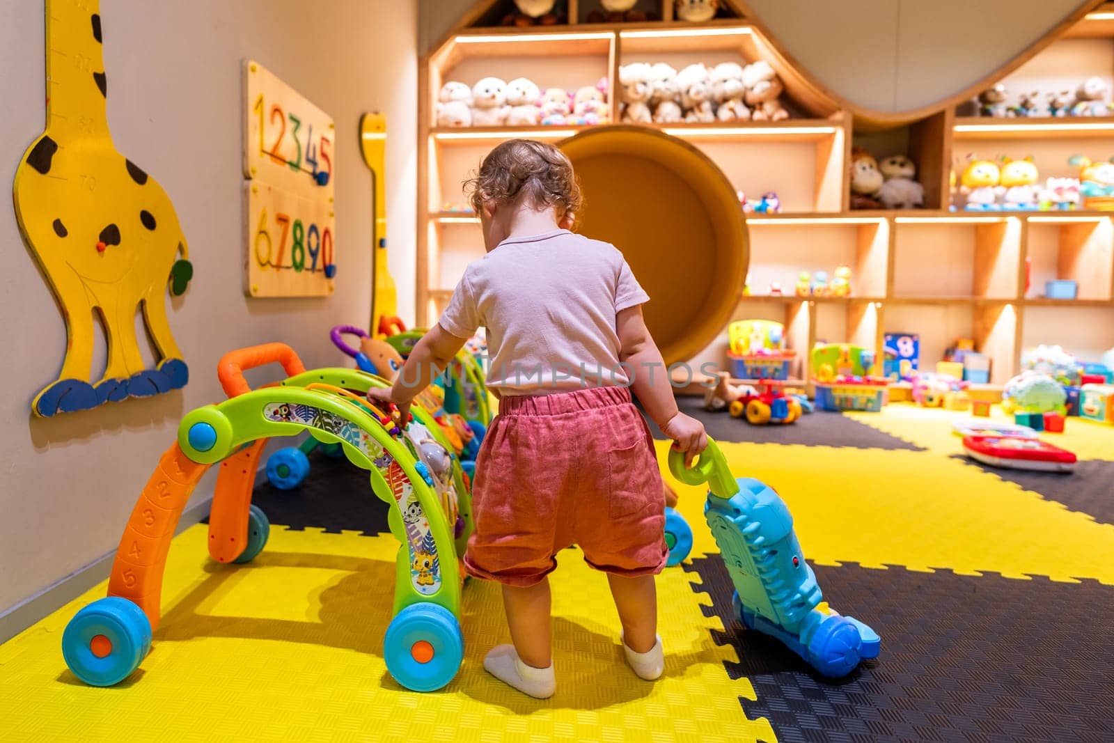 Kid exploring toys in a safe playroom with educational activities and soft flooring