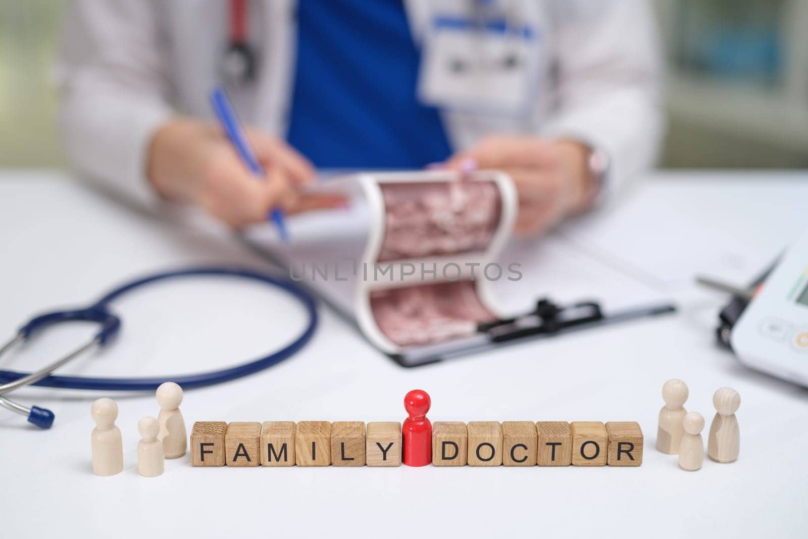A family doctor reviews key medical info using wooden figures and a stethoscope during the consultation