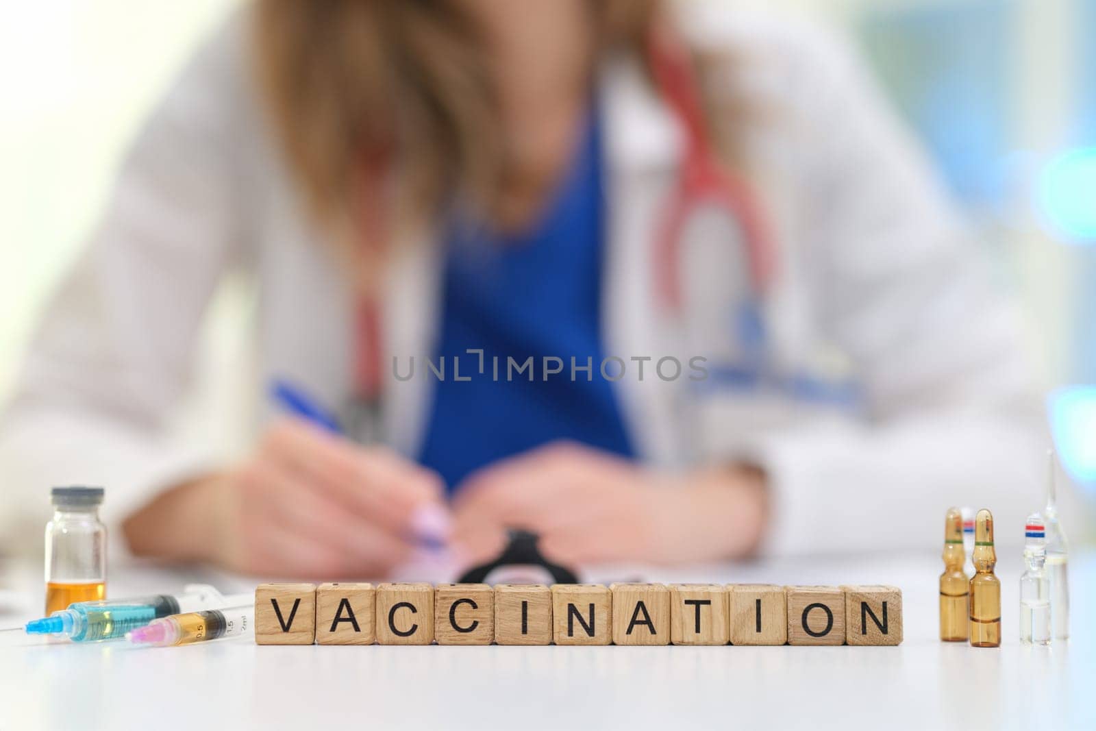 A healthcare professional emphasizes the importance of vaccination with vials and blocks spelling 'VACCINATION'.