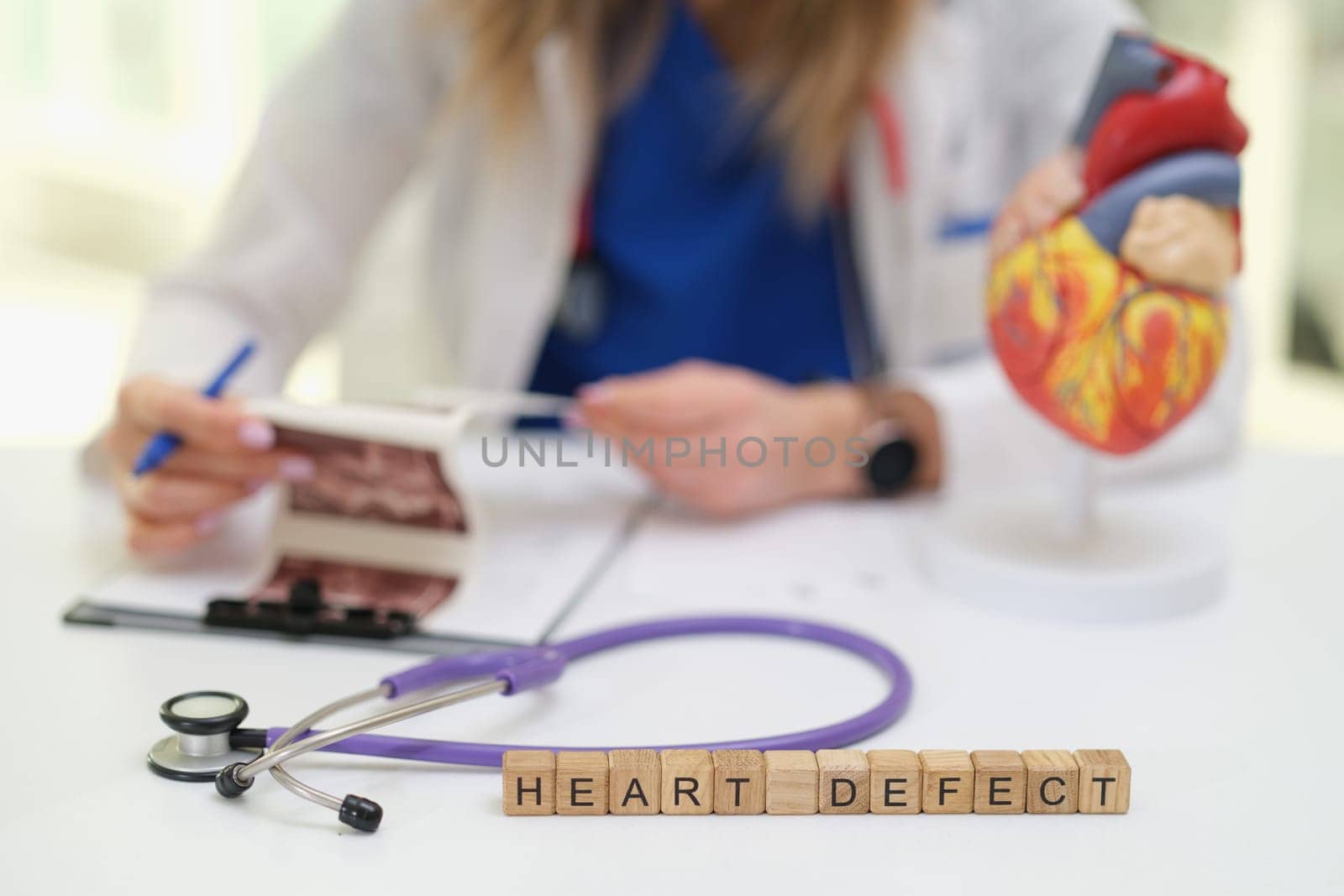 A skilled medical professional thoroughly examines heart defect images using a stethoscope and a model heart