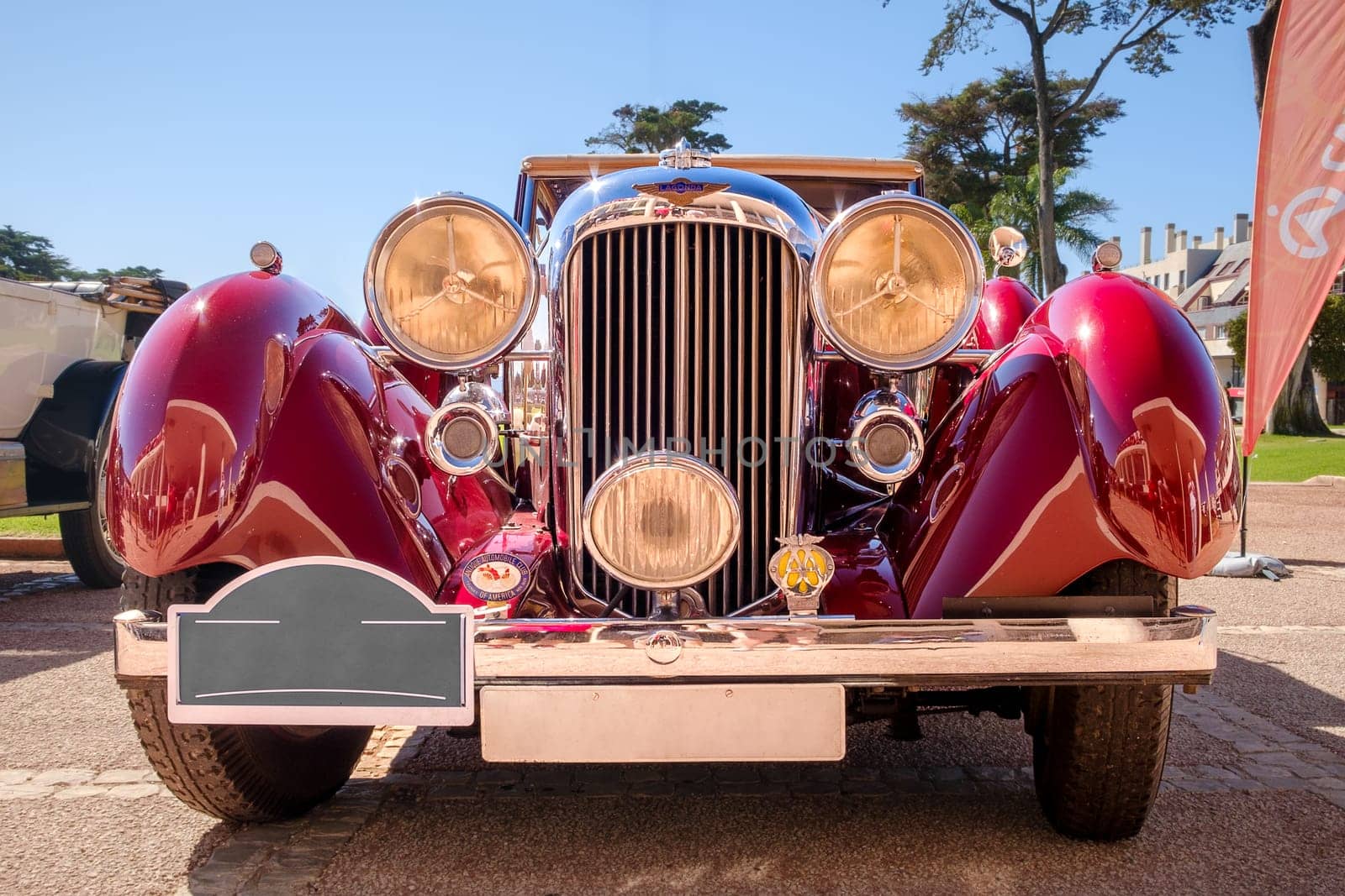 Lisbon, Portugal - Sep 29, 2024: Front view of vintage red Lagonda LG45 on sunny day. Bumper, headlighst, grille with badge and logo of luxury sports car of 1930s, 2-door drophead coupe version, Lagonda, UK