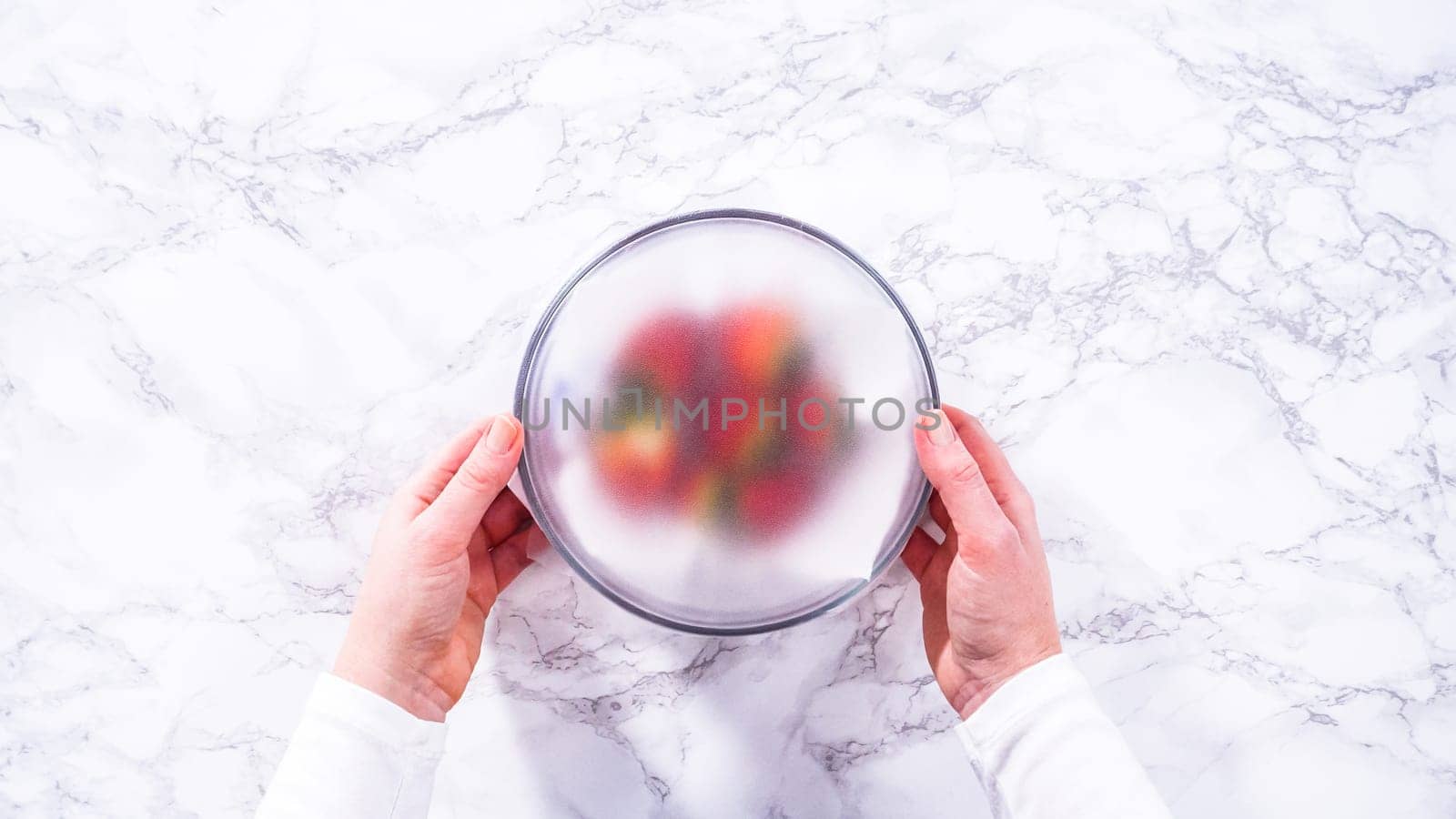 Flat lay. Strawberries, freshly washed and dried, are neatly stored in a glass bowl lined with a paper towel and securely covered with plastic wrap to maintain freshness.