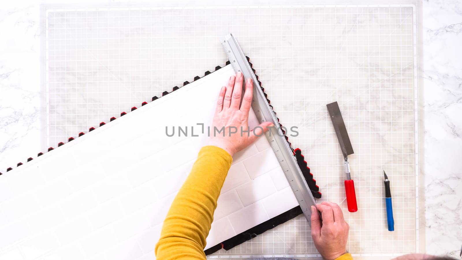 Flat lay. In the process of mounting peel and stick mosaic tiles onto a foam board, perfect for enhancing a food photography studio's aesthetic.