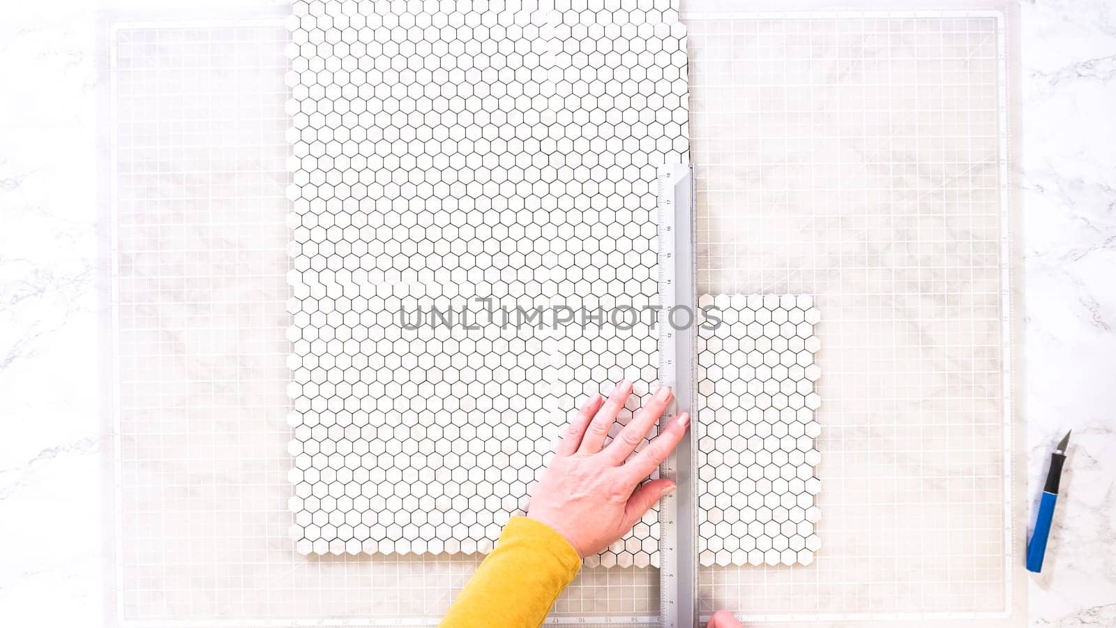 Flat lay. In the process of mounting peel and stick mosaic tiles onto a foam board, perfect for enhancing a food photography studio's aesthetic.