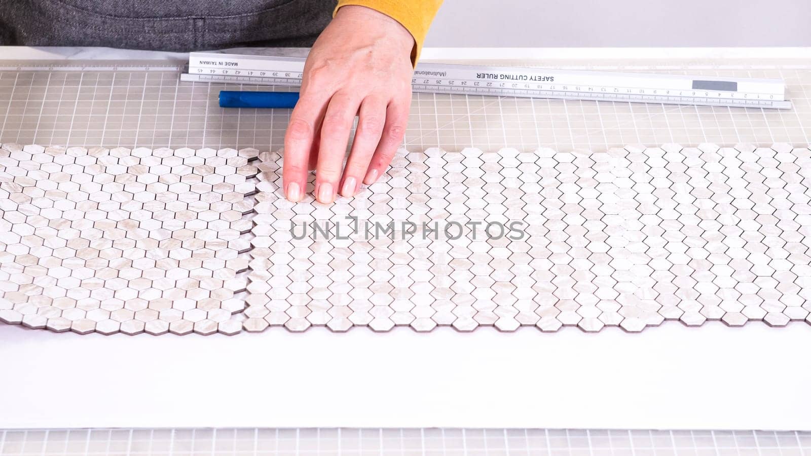 In the process of mounting peel and stick mosaic tiles onto a foam board, perfect for enhancing a food photography studio's aesthetic.