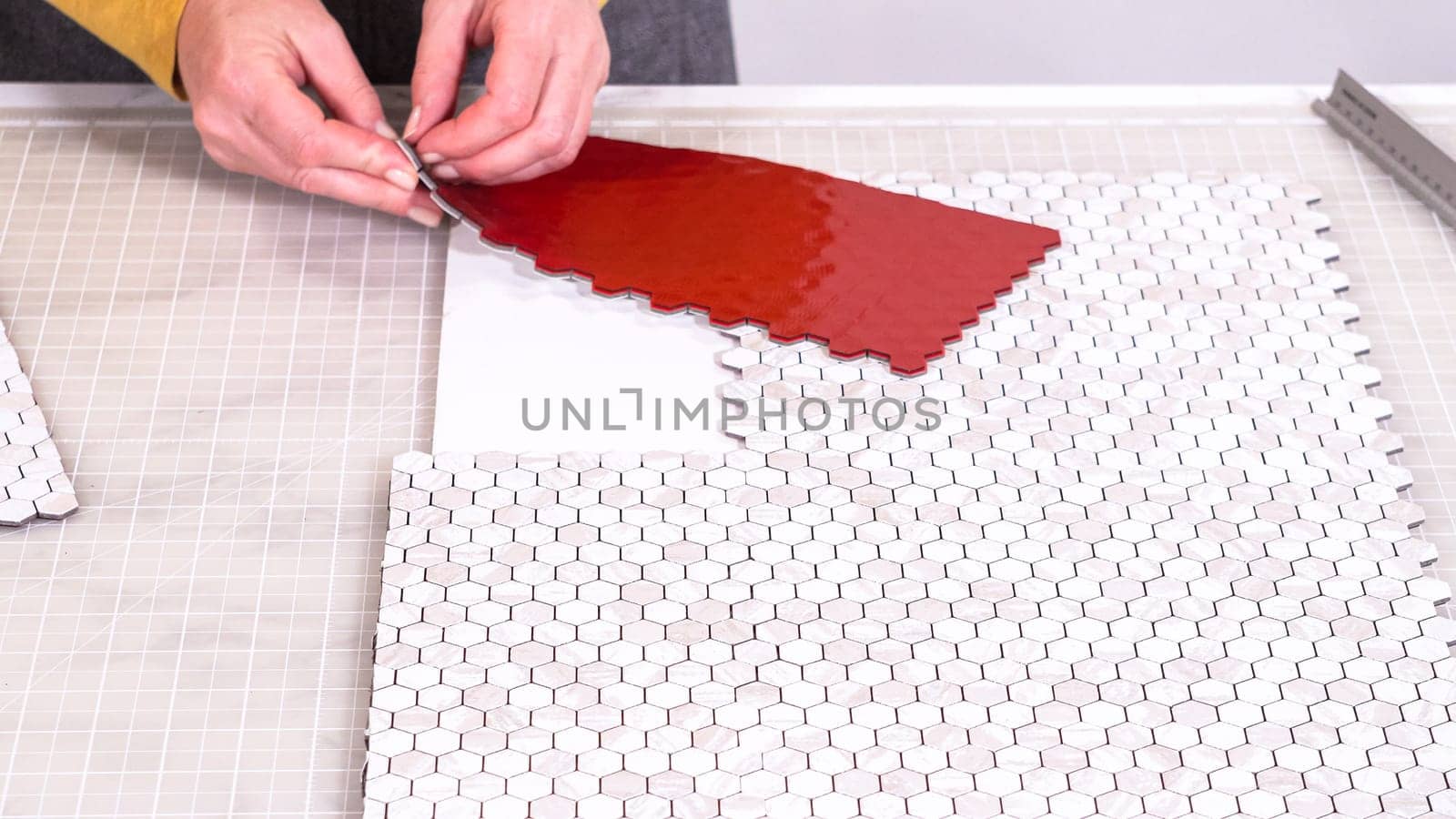 In the process of mounting peel and stick mosaic tiles onto a foam board, perfect for enhancing a food photography studio's aesthetic.