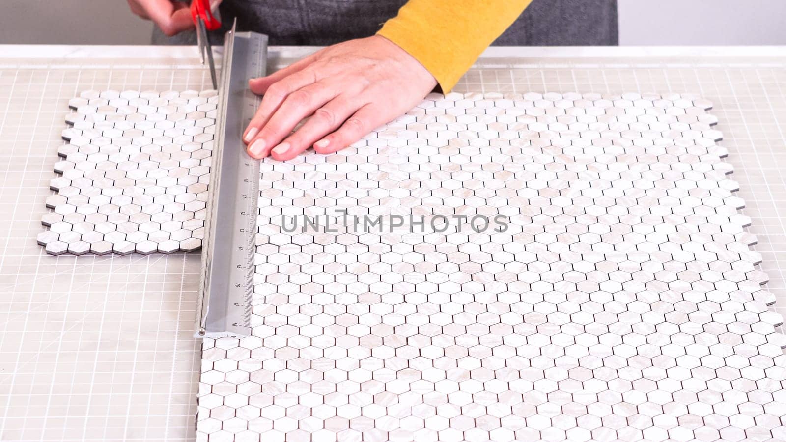 In the process of mounting peel and stick mosaic tiles onto a foam board, perfect for enhancing a food photography studio's aesthetic.