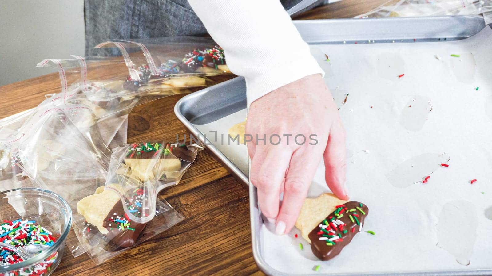 Carefully packaging Christmas cutout cookies, half-dipped in chocolate and presented in clear cellophane wrapping, perfect for festive gifting.