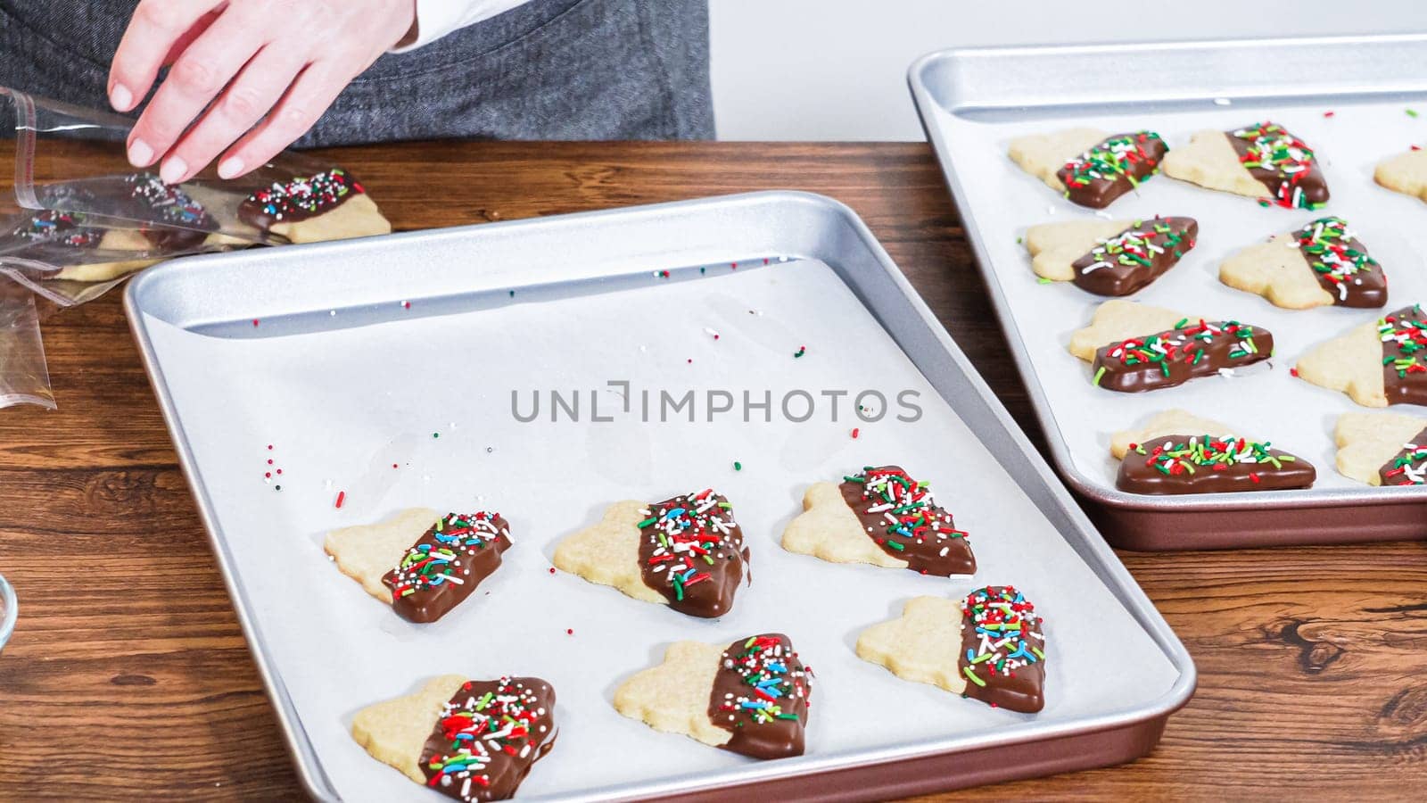 Carefully packaging Christmas cutout cookies, half-dipped in chocolate and presented in clear cellophane wrapping, perfect for festive gifting.
