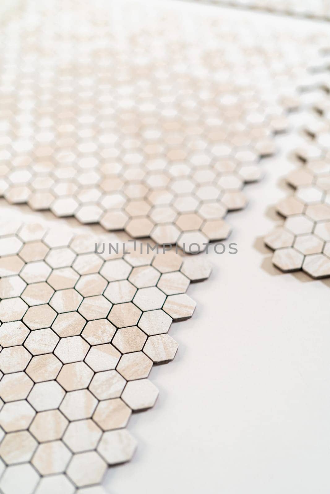 In the process of mounting peel and stick mosaic tiles onto a foam board, perfect for enhancing a food photography studio's aesthetic.