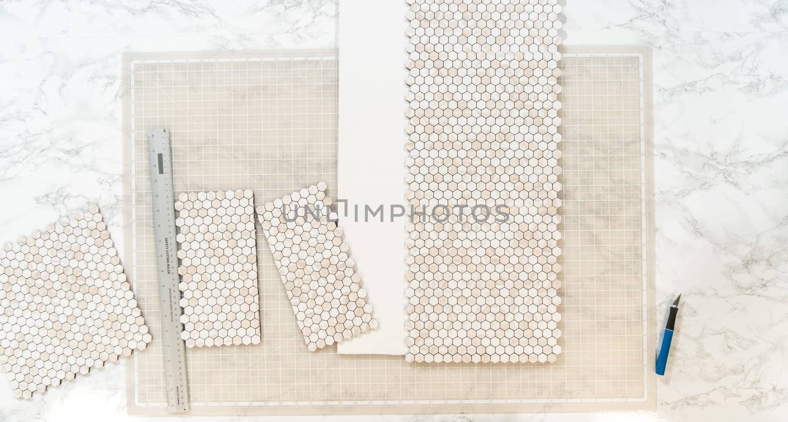In the process of mounting peel and stick mosaic tiles onto a foam board, perfect for enhancing a food photography studio's aesthetic.