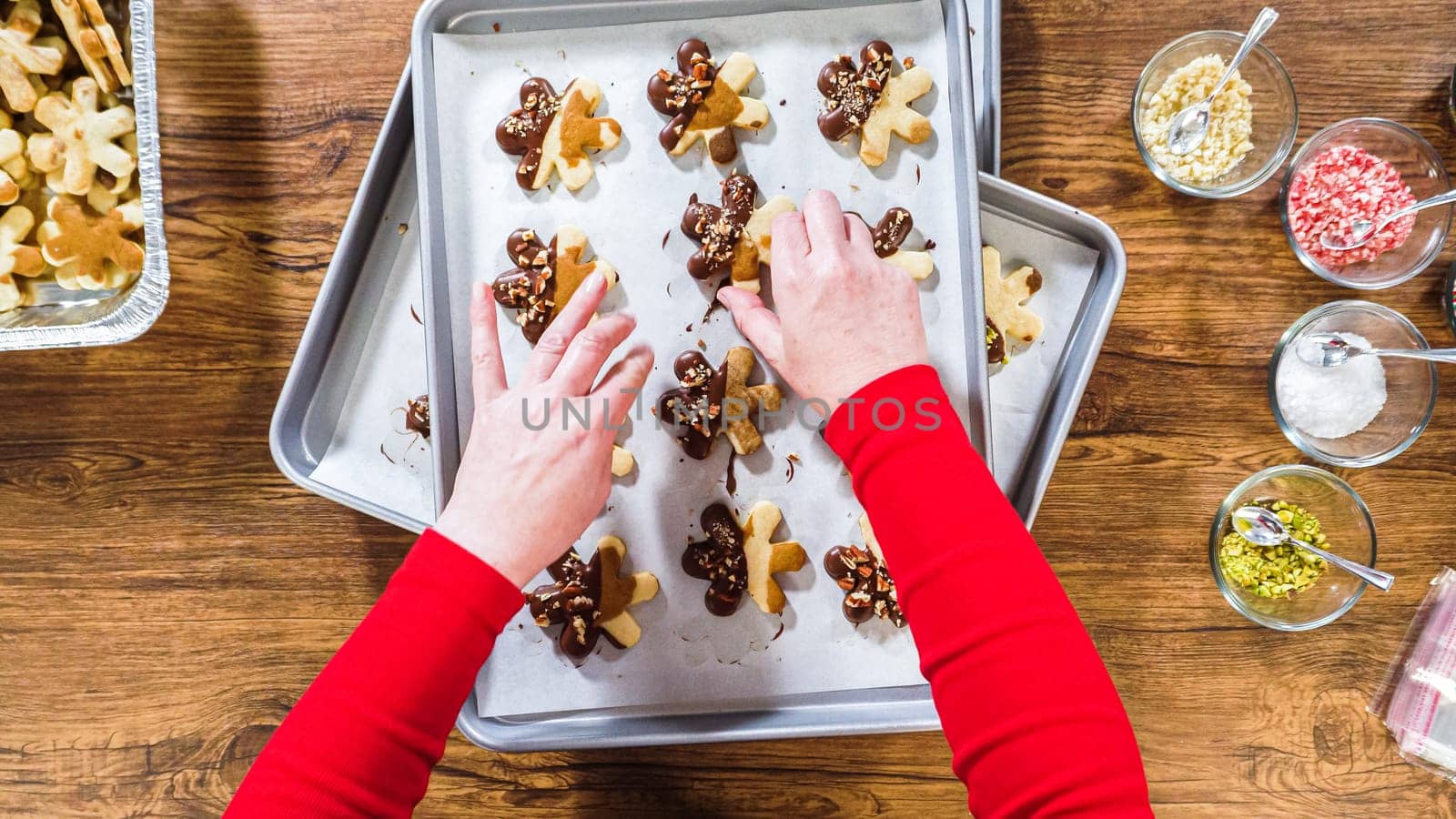 Flat lay. Carefully packaging Christmas cutout cookies, half-dipped in chocolate, sprinkled with crushed nuts, and presented in clear cellophane wrapping.