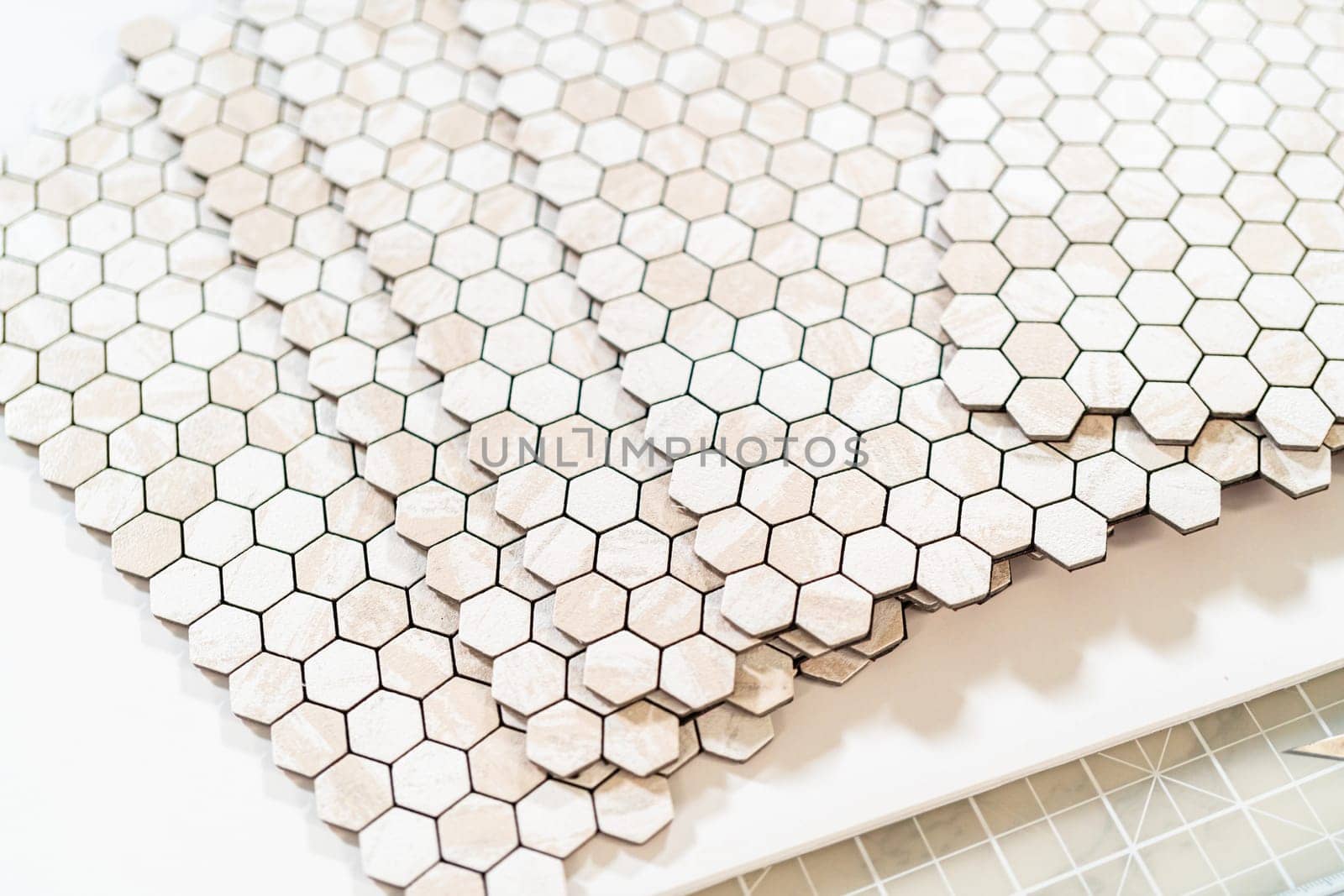 In the process of mounting peel and stick mosaic tiles onto a foam board, perfect for enhancing a food photography studio's aesthetic.