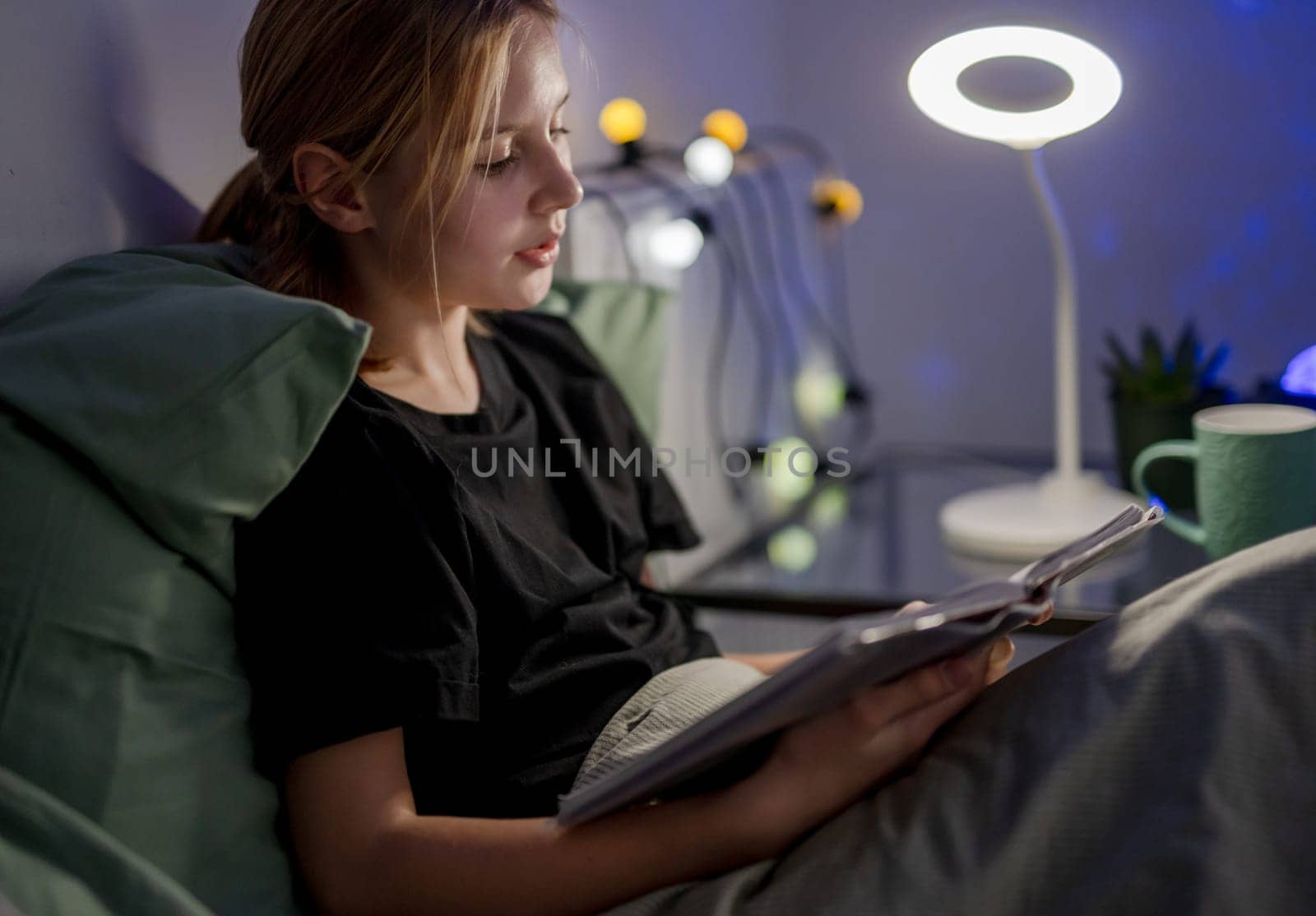 Cute Little Girl In Bed Reading A Book Aloud Before Sleep