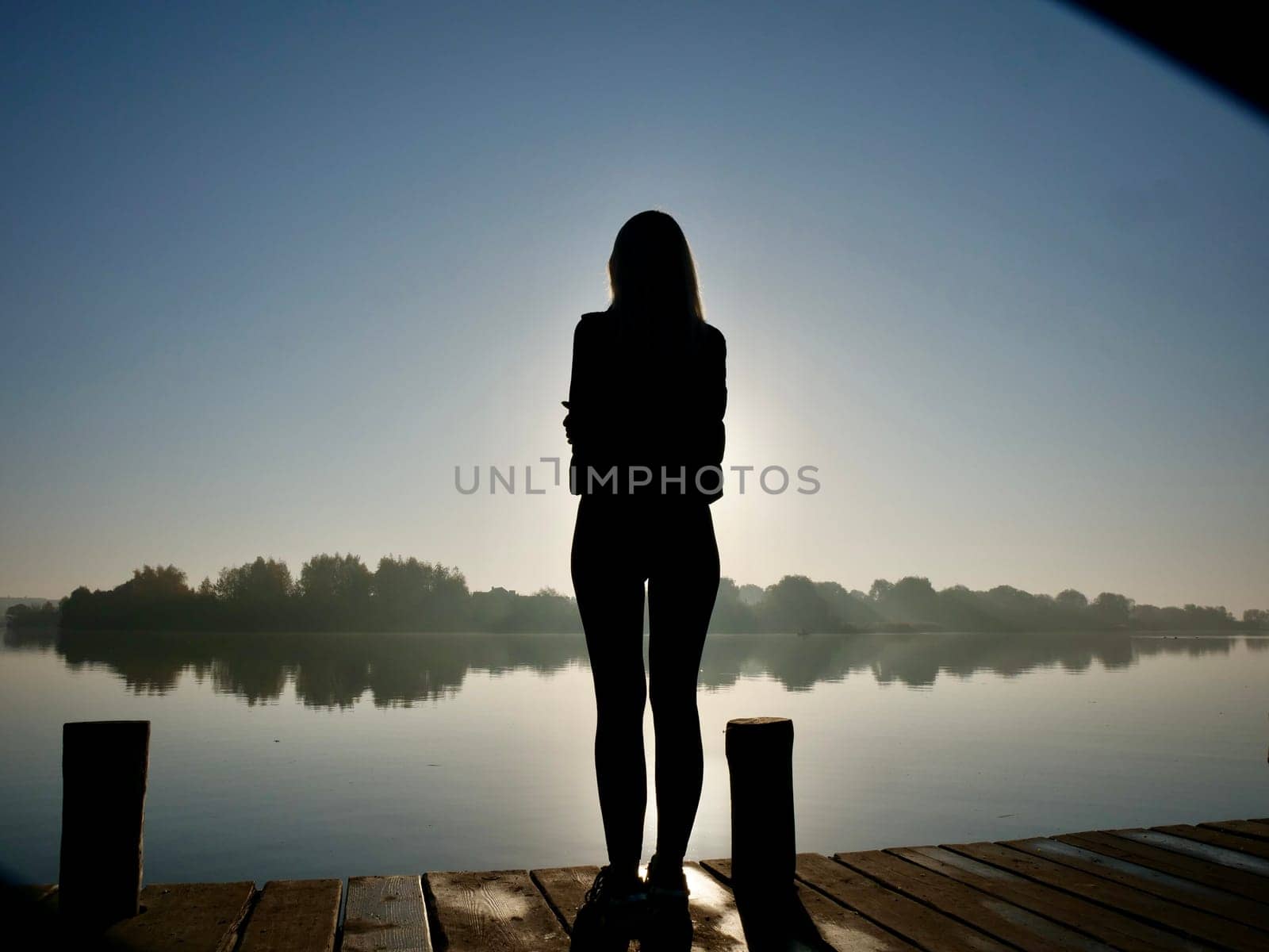 Woman standing on sadhu board, process of standing barefoot on nails, view of feet practicing yoga and meditation outdoors, autumn day near lake at sunrise