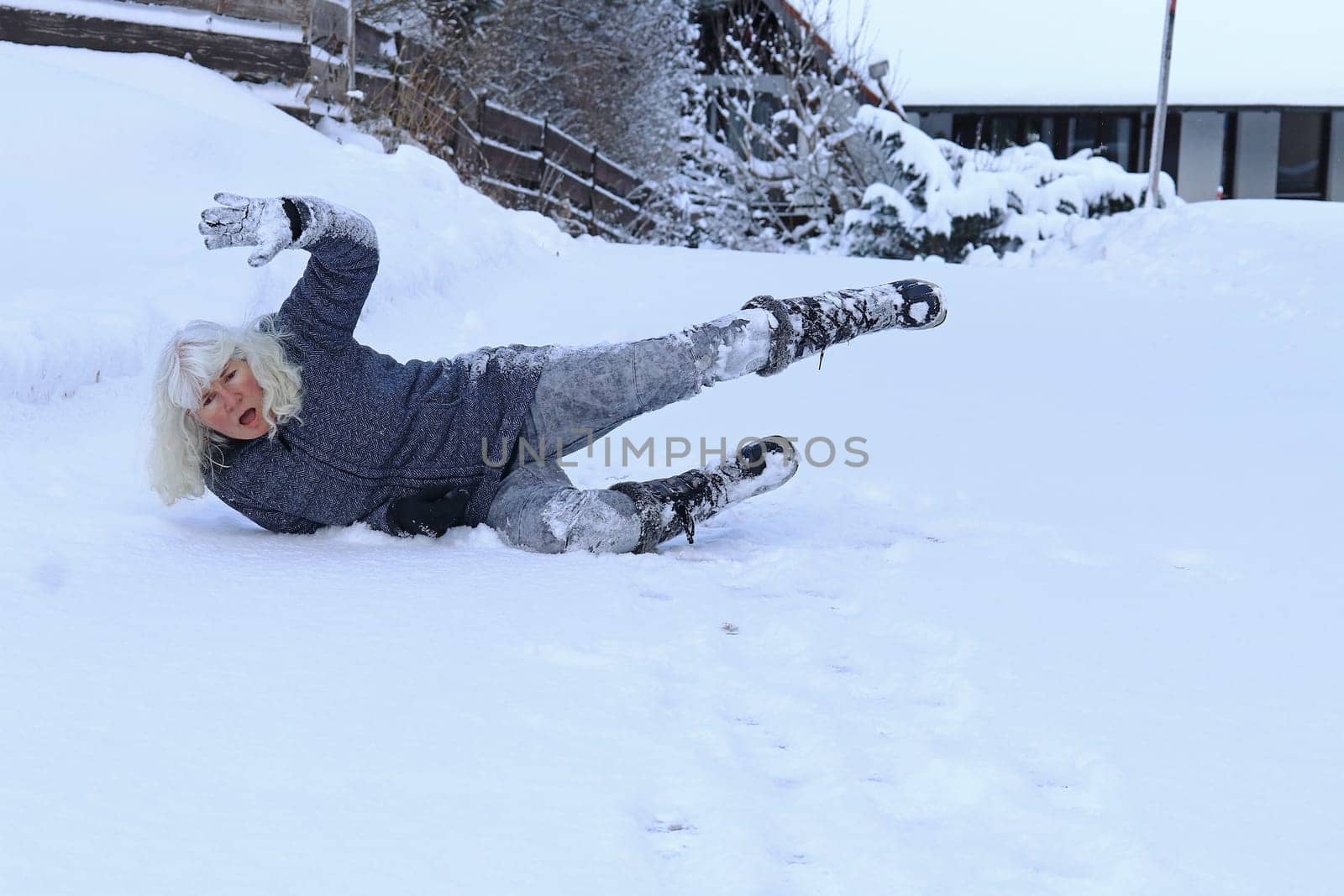 Rutschgefahr auf einer glatten Straße im Winter. Eine Frau ist auf dem Schnee ausgerutscht und hingefallen