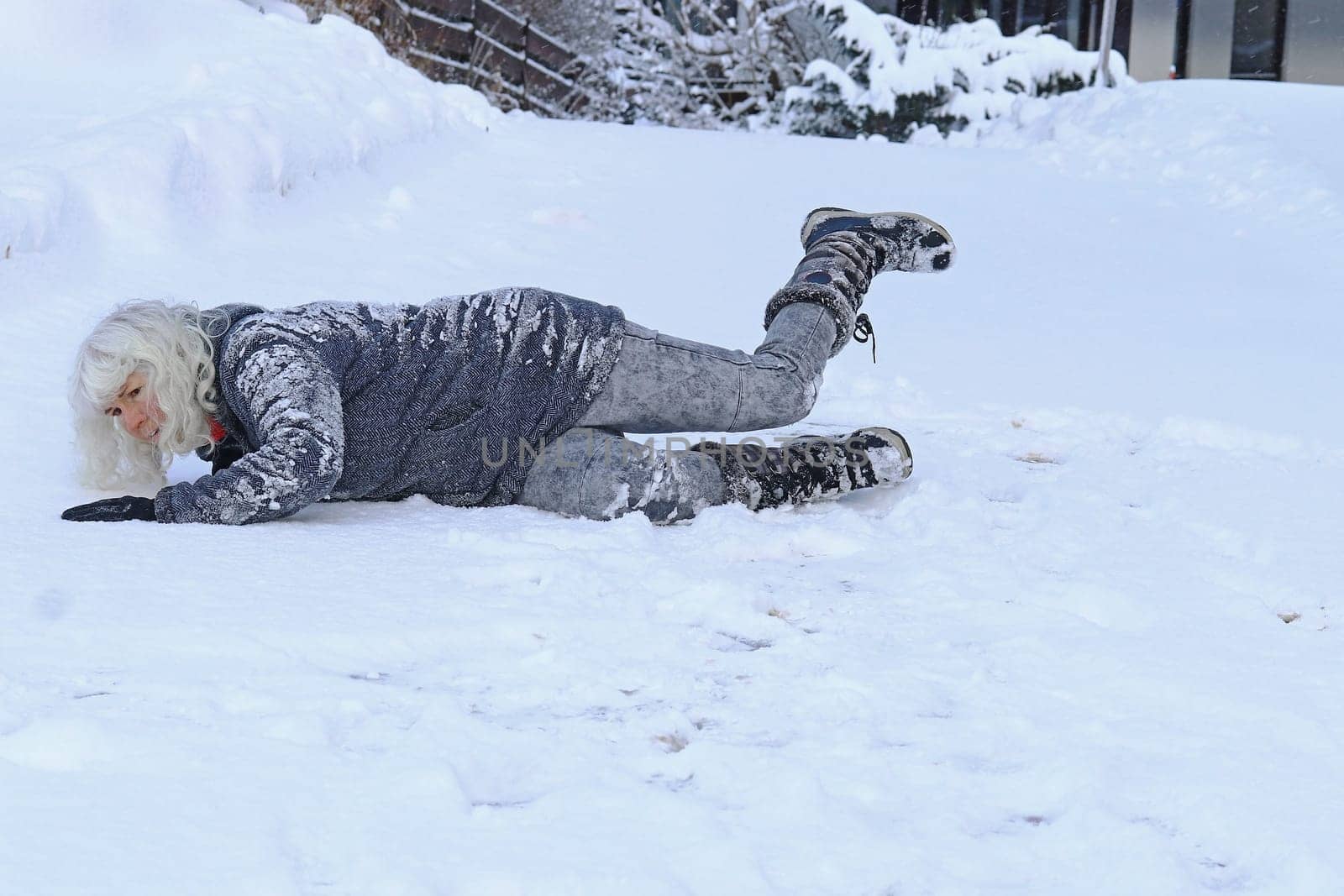 Rutschgefahr auf einer glatten Straße im Winter. Eine Frau ist auf dem Schnee ausgerutscht und hingefallen